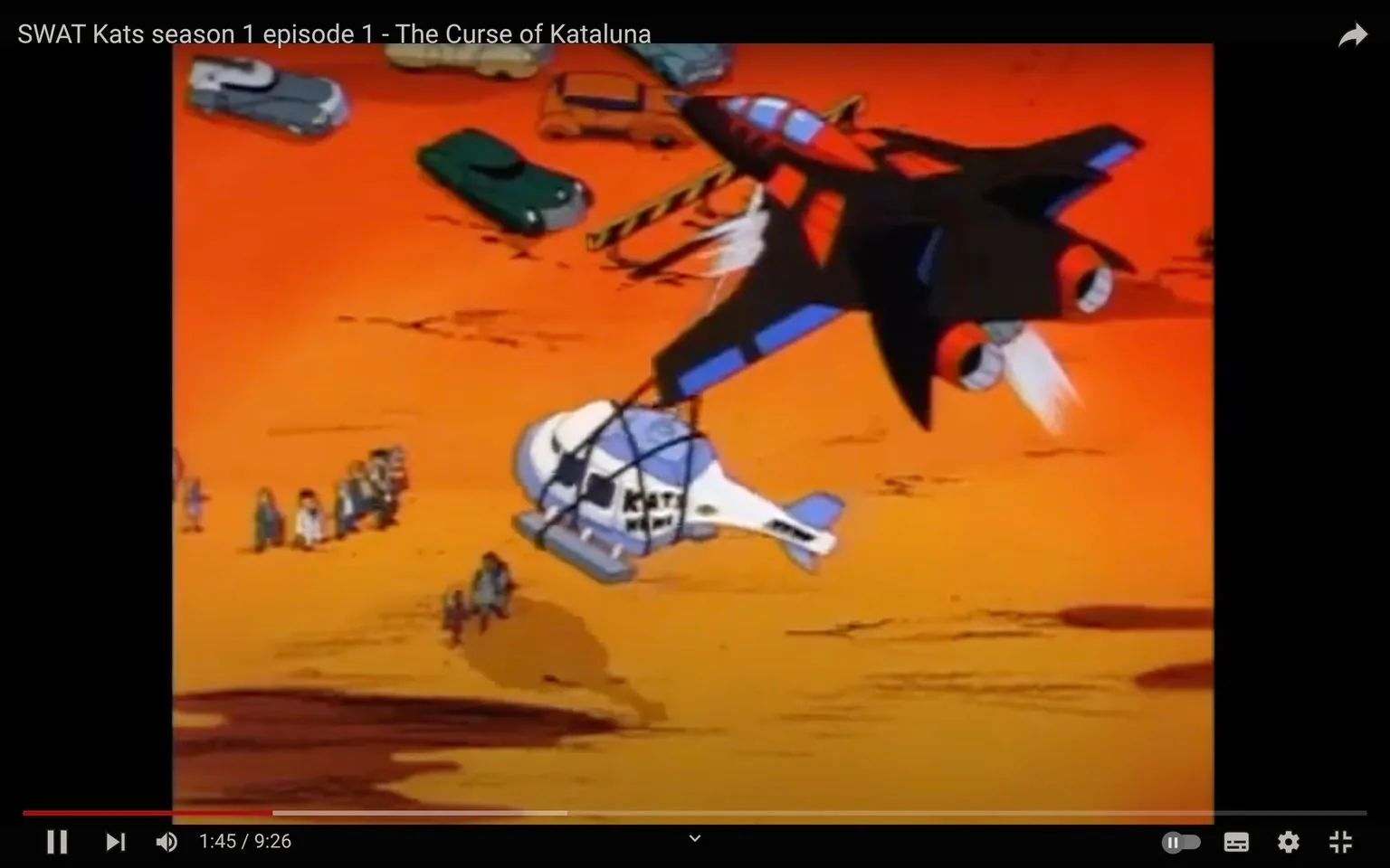 The image is a frame from the animated series "SWAT Kats," specifically from season 1 episode 1 titled "The Curse of Kataluna." The scene features a vibrant, animated desert landscape with a bright orange hue dominating the background. In the air, a distinctive black and red jet is seen carrying a helicopter marked with "KAT." The jet and helicopter are central to the composition, highlighting the series' focus on action and technology. Below, several animated characters are gathered around various vehicles, suggesting a scene of activity or confrontation. The animation style is typical of 1990s cartoons, with bold colors and exaggerated designs. The setting implies a high-energy sequence, possibly involving rescue or pursuit, characteristic of the SWAT Kats' adventurous themes.