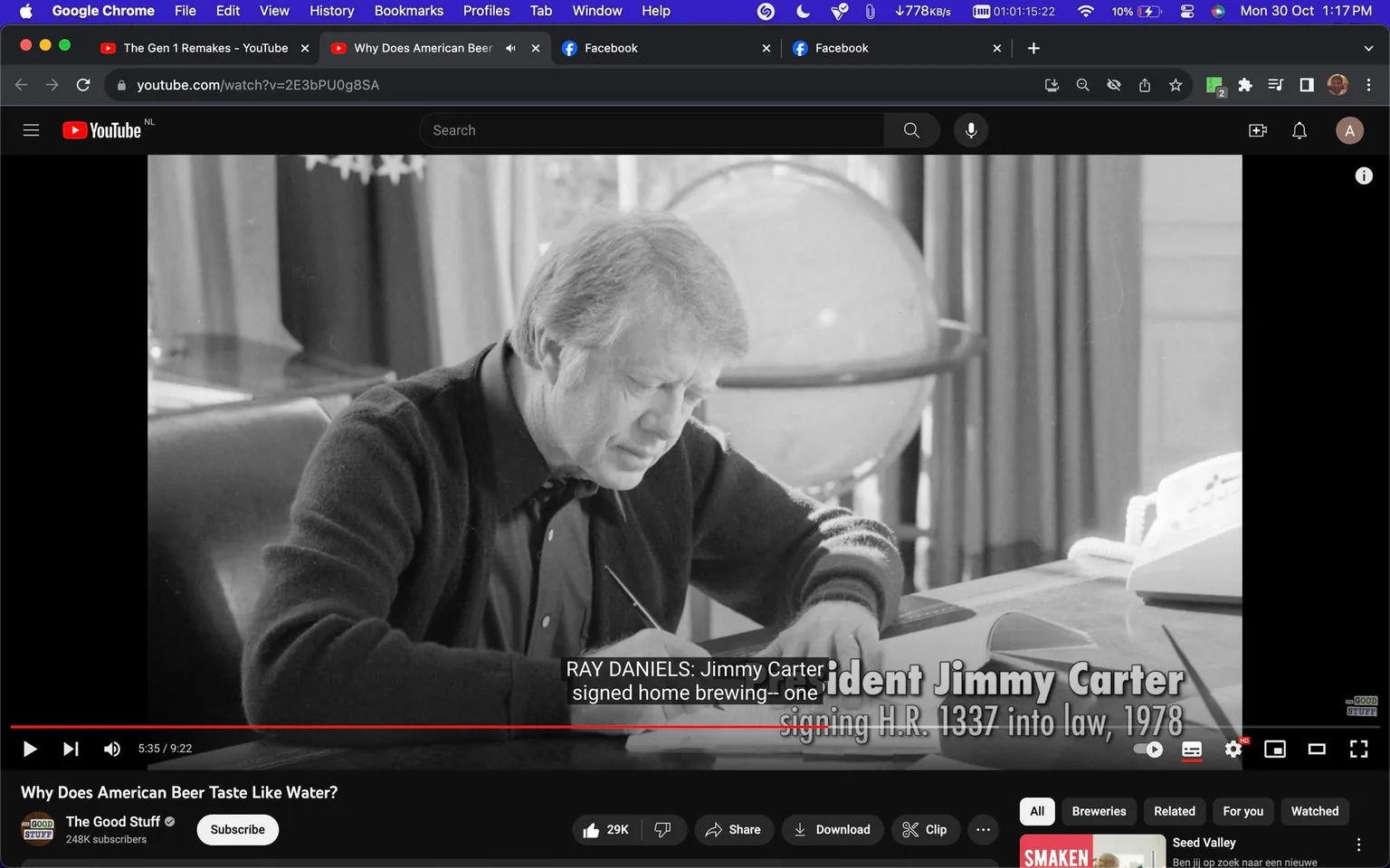 The screenshot captures a historical black and white image from a YouTube video titled "Why Does American Beer Taste Like Water?" featured on the channel "The Good Stuff." The scene shows President Jimmy Carter sitting at a desk in an office setting, captured during a moment of focus as he appears to be signing a document. In the background, there's a globe and some drapery, adding a formal office ambiance. The video subtitle reads, "RAY DANIELS: Jimmy Carter signed home brewing--one," and the on-screen text indicates "President Jimmy Carter signing H.R. 1337 into law, 1978." This image is part of a discussion about the legislation that influenced American beer production, with particular emphasis on home brewing. The overall tone of the image is serious and reflective, highlighting a significant moment in brewing history.