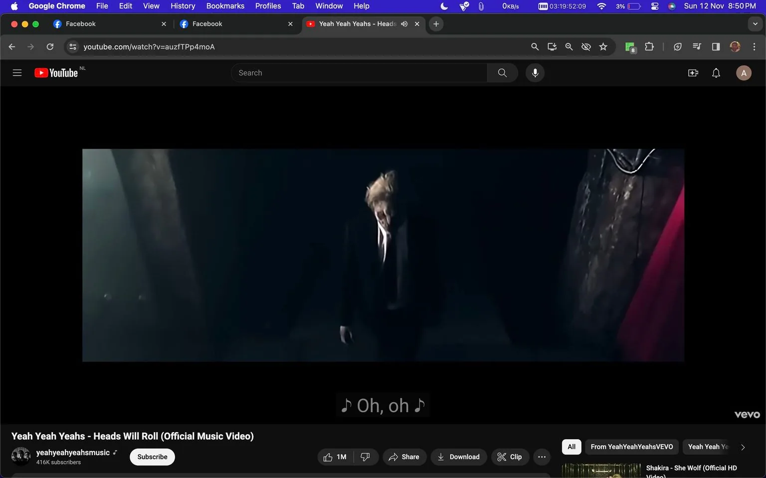 The image is a screenshot from a YouTube video titled "Yeah Yeah Yeahs - Heads Will Roll (Official Music Video)" on the channel "yeahyeahyeahsmusic." The scene is dark and dramatic, featuring a person dressed in a formal suit and tie, standing in a dimly lit space. The lighting is low, casting shadows that enhance the somber and intense mood of the video. The individual appears to be in motion, perhaps walking or dancing, which aligns with the dynamic nature of a music video. The background is obscured, focusing attention on the figure in the foreground. Subtitles are present at the bottom of the screen, displaying the lyrics "♪ Oh, oh ♪," indicative of a musical performance. The video is from the band Yeah Yeah Yeahs, and the visual style reflects the band's edgy and artistic aesthetic.
- Title: "Yeah Yeah Yeahs - Heads Will Roll (Official Music Video)"
- Channel / profile: "yeahyeahyeahsmusic"
- Site / app: "YouTube"
- Captions / subtitles: "♪ Oh, oh ♪"