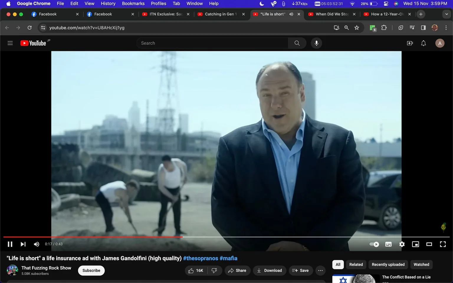 The image is a screenshot from a video on YouTube titled "\"Life is short\" a life insurance ad with James Gandolfini (high quality)". The channel hosting the video is "That Fuzzing Rock Show". The video features Mr. James Gandolfini, whom the viewer recognizes from "Sesame Street". The scene is set outdoors in an industrial area, with a city skyline and power lines visible in the background.
In the foreground, Mr. James Gandolfini is dressed in a dark suit and a light blue shirt, speaking directly to the camera, likely delivering a line from the commercial. His expression is serious and engaged, fitting the tone of a life insurance advertisement. Behind him, two individuals are seen working, shoveling dirt, which adds an element of activity and context to the setting. The lighting is bright, suggesting a clear day. No specific branding or text is visible in the frame apart from the video title and channel information. The tags associated with the video suggest connections to popular culture themes like "thesopranos" and "mafia".