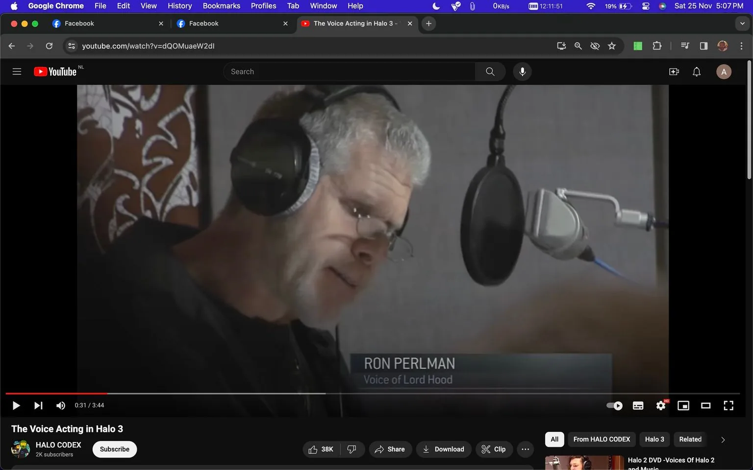 Ron Perlman is featured in a YouTube video titled "The Voice Acting in Halo 3," which is on the HALO CODEX channel. This screenshot captures him in a recording studio, demonstrating his voice acting skills for the character Lord Hood in the game "Halo 3." Ron Perlman is wearing headphones and is positioned close to a microphone with a pop filter, suggesting he is in the midst of a voice recording session. The background features a patterned wall, adding a decorative element to the studio setting. The lighting is soft and focused on Perlman, emphasizing his concentration on the task. The interface shows the video has a duration of 3:44, and the progress bar indicates it is 31 seconds in. There is a visible overlay of text identifying him and his role, and the video has accumulated a significant number of likes, indicated by the "38K" thumbs-up icon.