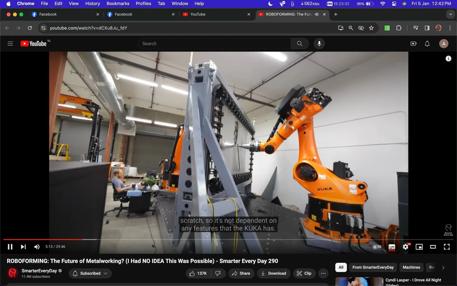 The screenshot depicts a YouTube video titled "ROBOFORMING: The Future of Metalworking? (I Had NO IDEA This Was Possible) - Smarter Every Day 290" from the channel SmarterEveryDay. The scene is set in an indoor workshop, featuring a large KUKA industrial robot arm engaged in a metalworking process. The robotic arm is bright orange and positioned on the right side, with a mechanical structure in the center, presumably part of the metal forming setup. In the background, a person is seated at a desk, working on a computer, suggesting an environment focused on advanced technology and engineering.
The lighting is bright and evenly distributed, typical of industrial settings. The video player interface is visible, with controls like play, pause, volume, and full screen, alongside a progress bar. The video is at the 5:13 mark in a total duration of 29:46 minutes. Subtitles are turned on, displaying the line, "scratch, so it's not dependent on any features that the KUKA has." The visual elements suggest a focus on innovation and automation in metalworking processes, aligning with the video's theme.