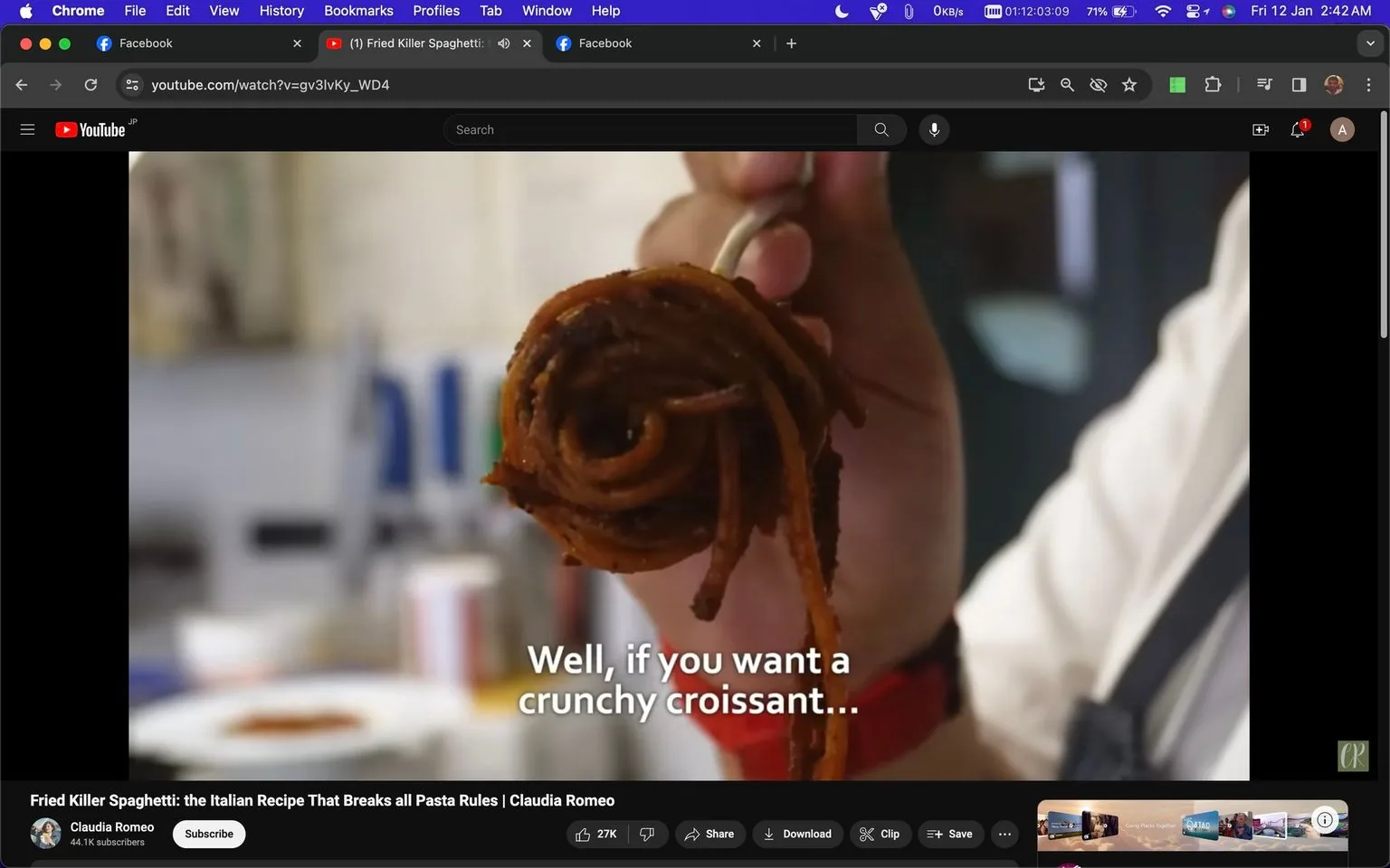 The image is a screenshot from a YouTube video titled "Fried Killer Spaghetti: the Italian Recipe That Breaks all Pasta Rules | Claudia Romeo," hosted on the channel "Claudia Romeo." It features a close-up view of a hand holding a fork with a tightly wound serving of fried spaghetti. The background is slightly blurred, typical of a kitchen environment, with some utensils and bottles visible, suggesting a cooking demonstration. The lighting is warm, highlighting the texture of the spaghetti, which appears crispy and golden brown, possibly seasoned.
A subtitle on the screen reads, "Well, if you want a crunchy croissant...," adding a humorous or intriguing twist to the presentation, perhaps indicating an unconventional approach to traditional pasta. At the top of the browser window, tabs for Facebook and another YouTube video are visible, along with various browser controls. The scene conveys a casual, informative cooking setting aimed at presenting a unique culinary technique.