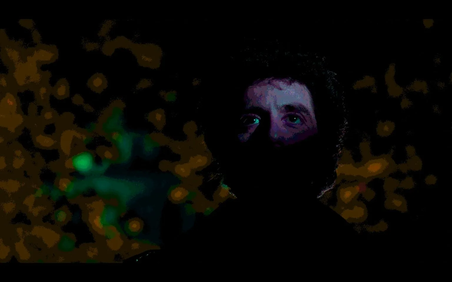The image is a dark and atmospheric scene from the film "Cruising" (1980), featuring Al Pacino. Al Pacino is pictured in a dimly lit setting, predominantly obscured by shadows, with only one side of his face partially visible. His eyes are slightly illuminated, capturing an intense and contemplative expression that adds to the mysterious mood of the scene. The background is a blur of soft, out-of-focus lights in green and orange hues, suggesting an urban environment. The lighting is dramatic, enhancing the film noir style of the film. The use of shadow and low light creates a sense of suspense and intrigue, characteristic of the movie's themes. This visual style is essential to the film's exploration of identity and the complex narrative.