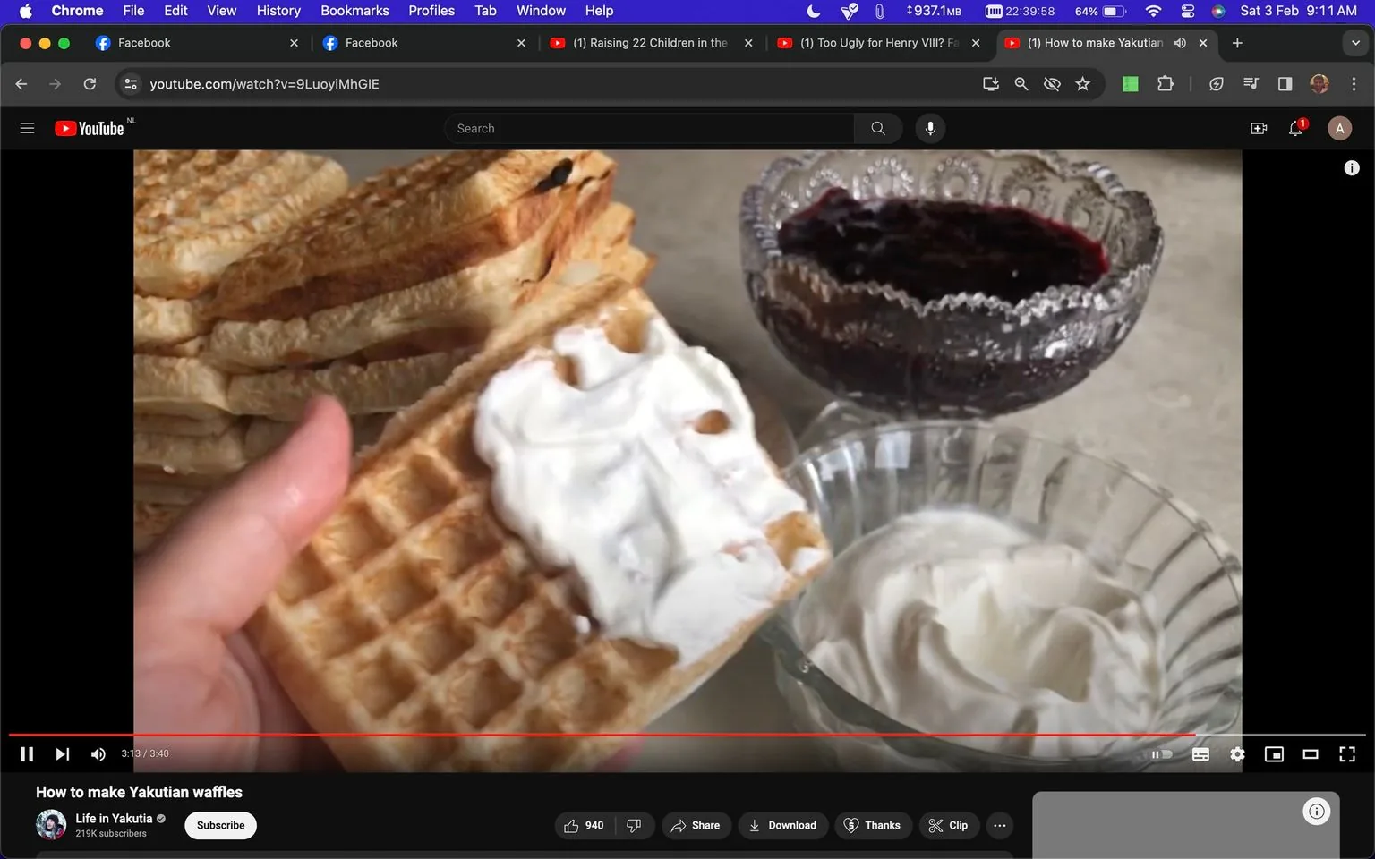 This image is a screenshot from a YouTube video titled "How to make Yakutian waffles" by the channel Life in Yakutia. The scene features a close-up view of a hand holding a waffle with a layer of cream spread on top. In the background, there are more waffles stacked neatly. Next to the waffles, there are two glass bowls: one containing dark syrup or jam and the other with more cream. The setting appears to be a kitchen or dining area with a neutral color scheme, focusing on the textures and colors of the food. The lighting is soft and natural, enhancing the appetizing appearance of the waffles. The video is likely a tutorial on making traditional Yakutian waffles, emphasizing homemade cooking and cultural cuisine. The YouTube interface is visible, showing standard video controls and options for likes, shares, and comments.