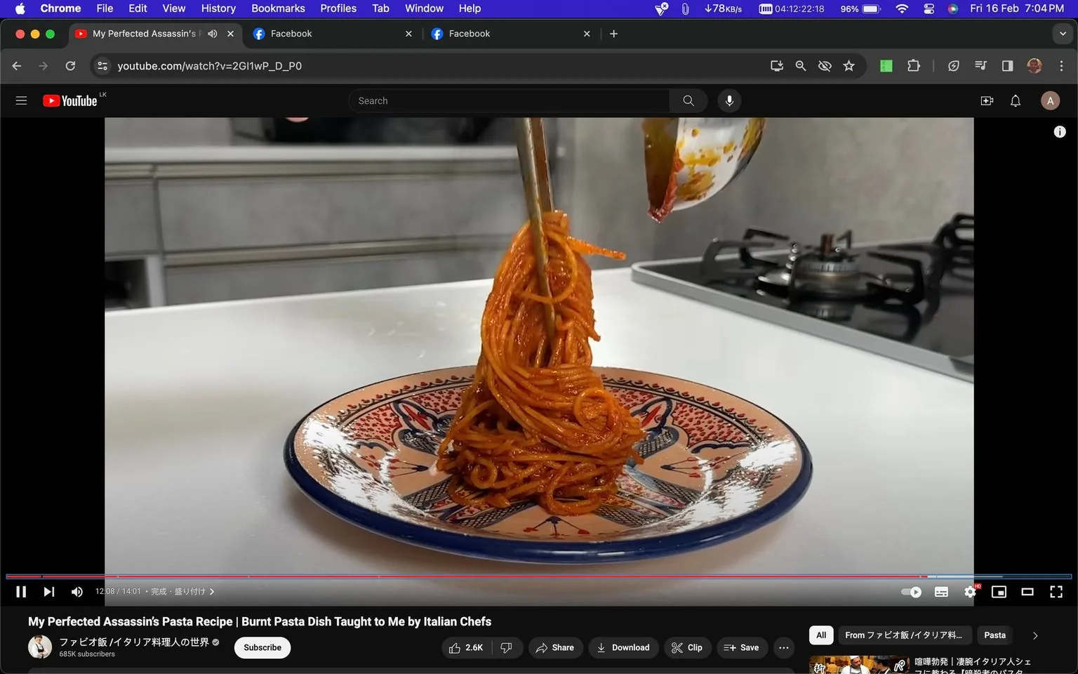 The screenshot captures a YouTube video titled "My Perfected Assassin's Pasta Recipe | Burnt Pasta Dish Taught to Me by Italian Chefs," featured on the channel "ファビオ飯 / イタリア料理人の世界." The video appears to focus on a unique pasta recipe known as Spaghetti al Assassina, as hinted in the nearby post. In the image, a portion of spaghetti is being elegantly twirled onto a decorative plate with a colorful, intricate design. The setting is a modern kitchen, with a stovetop visible in the background, indicating a culinary environment. The pasta is richly coated in a red sauce, suggesting a tomato-based dish. The lighting is bright, enhancing the presentation of the pasta on the plate. The image is paused at the 12:08 mark of a 14:01-long video, with options to like, share, download, and save below the video, emphasizing viewer engagement features typical of YouTube.