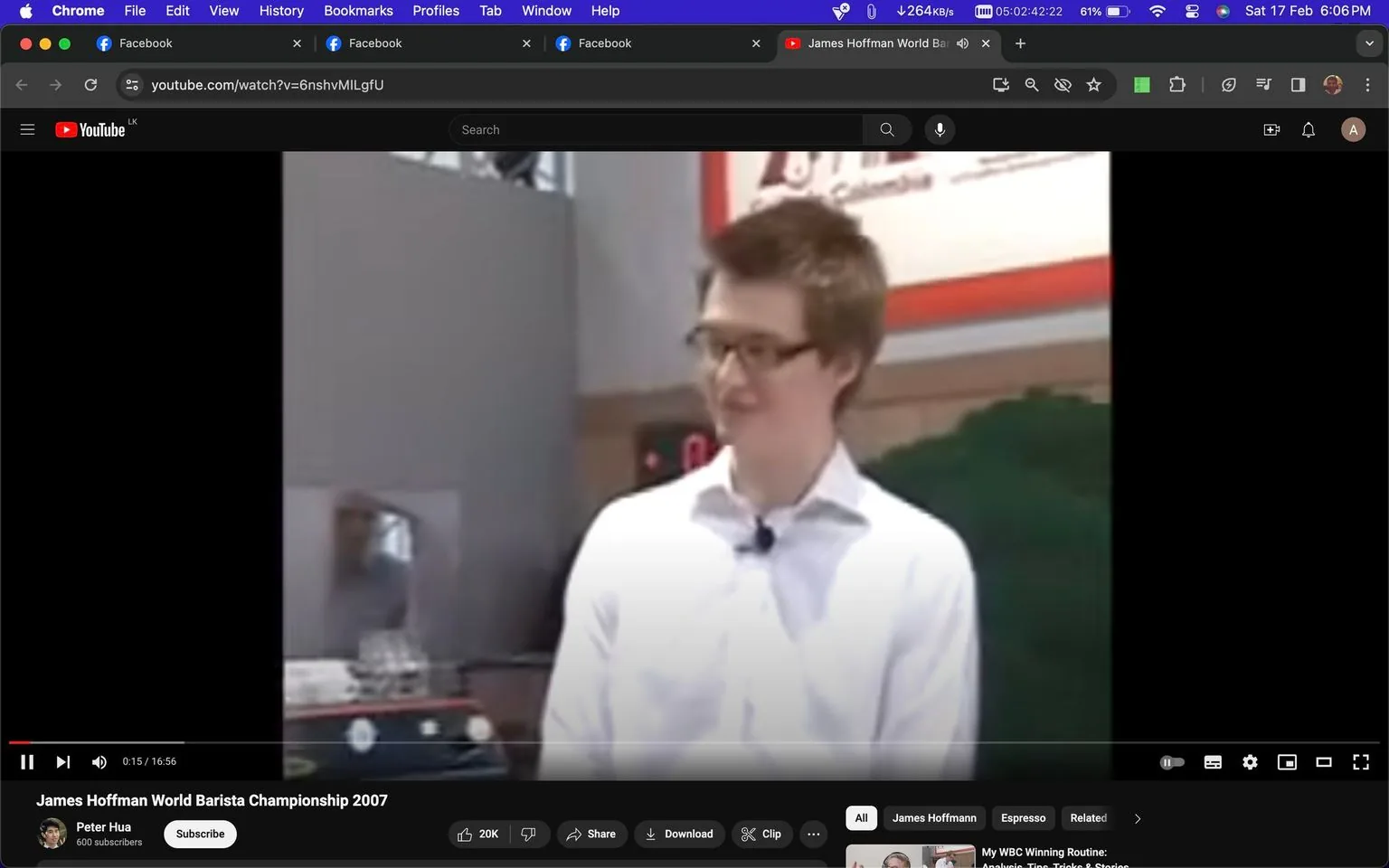 The screenshot is from a YouTube video titled "James Hoffman World Barista Championship 2007," uploaded by the channel Peter Hua. It shows an indoor setting where an individual is likely participating in a barista competition. The person is wearing glasses and a white shirt, standing in front of what appears to be a coffee machine or similar equipment, suggesting a coffee-related event. The setting is well-lit, with some banners or signs partially visible in the background, and it captures a moment in an apparent presentation or demonstration. The atmosphere seems professional, indicating a competitive or formal event context. The video is related to the coffee industry, focusing on a barista championship featuring James Hoffman.