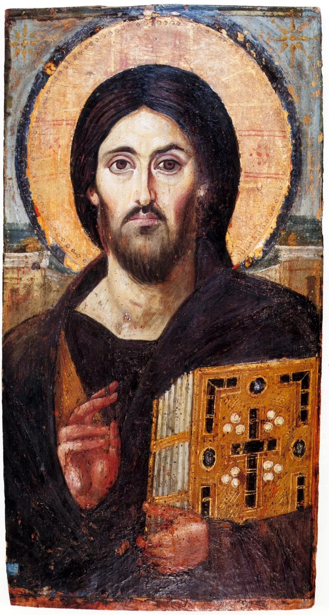 This image is a classic religious icon, featuring the depiction of Jesus Christ, known as "Christ Pantocrator." The artwork, in traditional Byzantine style, shows Jesus with a solemn expression, set against a golden-hued background that suggests a halo. The figure is portrayed holding a richly decorated book in his left hand, symbolizing the Gospels, while his right hand is raised in a gesture of blessing. His robes are dark, possibly a deep brown or black, providing a contrast to the lighter background and the ornate detail of the book. The icon employs vivid, earthy colors and intricate detailing typical of Byzantine religious art, emphasizing both holiness and authority. The facial features are stylized with large, expressive eyes and a beard, capturing a sense of divine serenity. The icon exemplifies the blend of spiritual symbolism and artistic tradition, often used in Orthodox Christian worship and veneration. The use of gold and the formal posture of the figure reflect the sacred nature of the subject matter.
