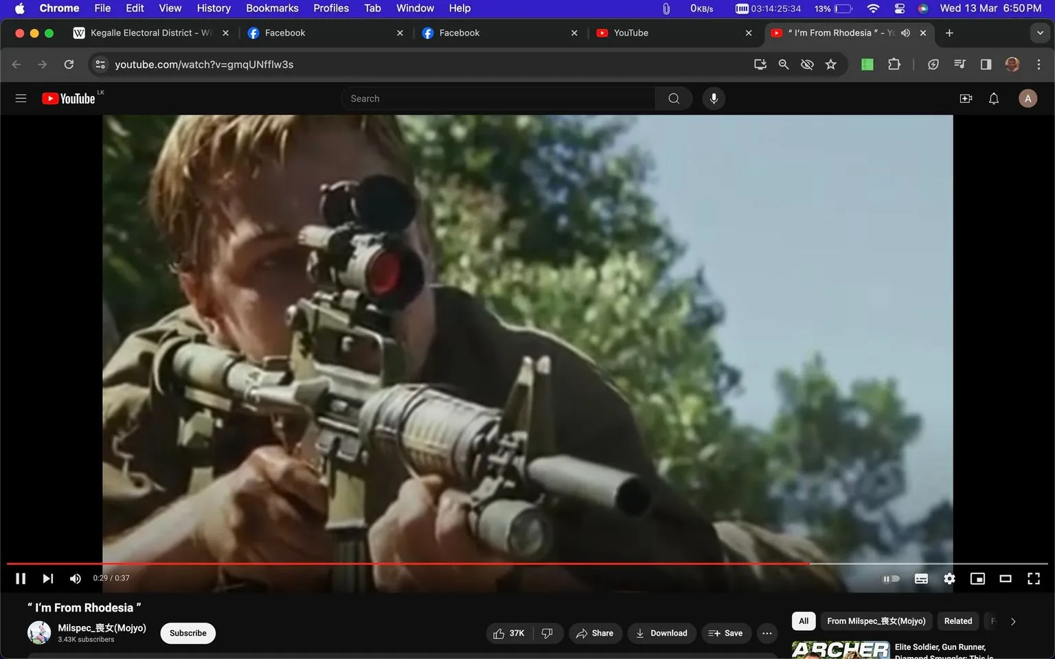 The screenshot shows a scene from a YouTube video titled “I’m From Rhodesia” on the channel Milspec-坂女(Moiyo). The scene features a person, hinted to be "Leo," aiming through a sniper rifle with a large scope. The setting appears to be outdoors, with a clear blue sky and some greenery in the background, indicating a daytime scene. The individual is positioned in a prone stance, suggesting stealth or defensive action, with a serious and focused demeanor. The rifle is detailed with attachments like a scope and possibly a suppressor, emphasizing the tactical nature of the scene. The interface of the video platform is visible, including options like like, share, and download, with details such as the number of views and subscribers. The overall composition conveys an intense and action-packed moment typical of a military or combat scenario.