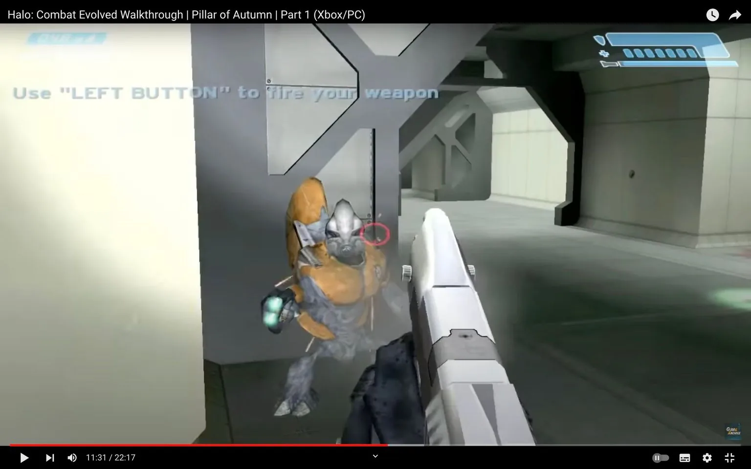 The image is a video frame from the "Halo: Combat Evolved" walkthrough, specifically from the "Pillar of Autumn" section, Part 1. The setting appears to be a futuristic, indoor environment, typical of a sci-fi video game. The first-person perspective shows a character holding a weapon, aiming at an alien enemy. The alien, with a distinctive orange armor and blue skin, is positioned close to a metallic wall, suggesting a combat scenario.
In the foreground, the gun is prominently displayed, aimed at the alien, indicating an active battle. The lighting is neutral, common in game environments to ensure visibility of characters and actions. The visual style is characteristic of early 2000s video game graphics, with polygonal models and relatively simple textures.
The on-screen text instructs the player to use the "LEFT BUTTON" to fire the weapon, providing gameplay guidance. The video is likely part of a series designed to help players navigate and succeed in "Halo: Combat Evolved," a well-known entry in the sci-fi shooter genre.