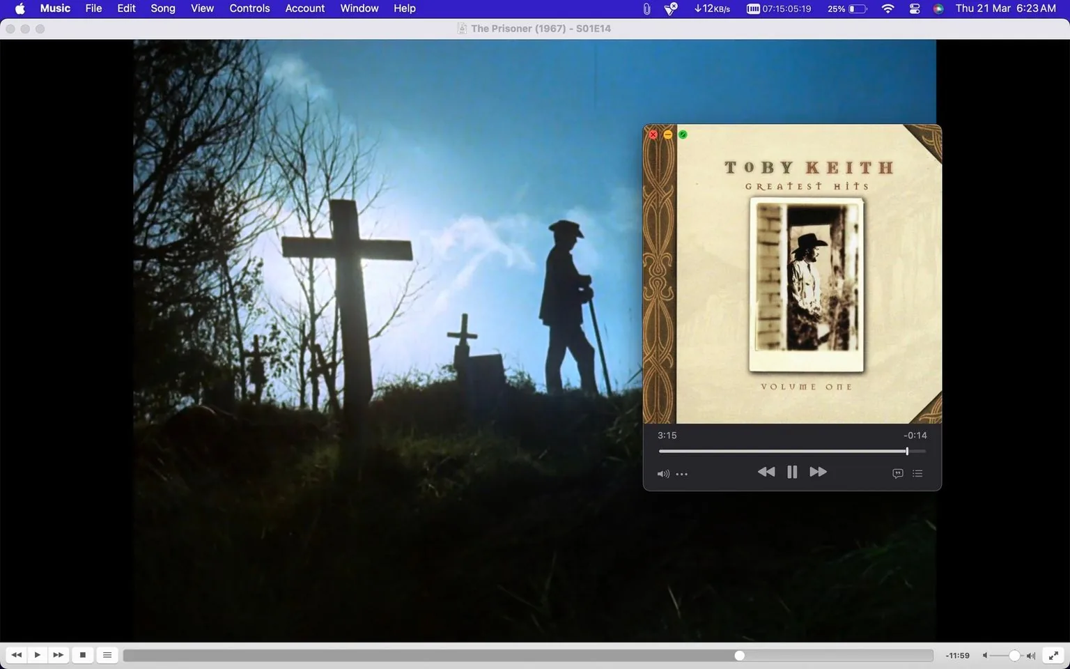 The image features a screenshot from a media player, likely "Music," showing an episode of "The Prisoner" from 1967, specifically Season 1, Episode 14. The scene in the background depicts a silhouette of a person walking with a stick in a graveyard. The lighting is dramatic, with a bright blue sky and the sun casting shadows, creating a serene but somber atmosphere. Crosses marking graves are visible, adding to the graveyard setting.
In the foreground, a smaller window overlays the scene, displaying an album cover for "Toby Keith Greatest Hits Volume One." The album cover features a sepia-toned image of a person in a cowboy hat, leaning against a wall, which is typical of Toby Keith's country music style. The text "TOBY KEITH," "GREATEST HITS," and "VOLUME ONE" appear prominently on the album cover.
- Title: "The Prisoner (1967) - S01E14"
- Site / app: "Music"