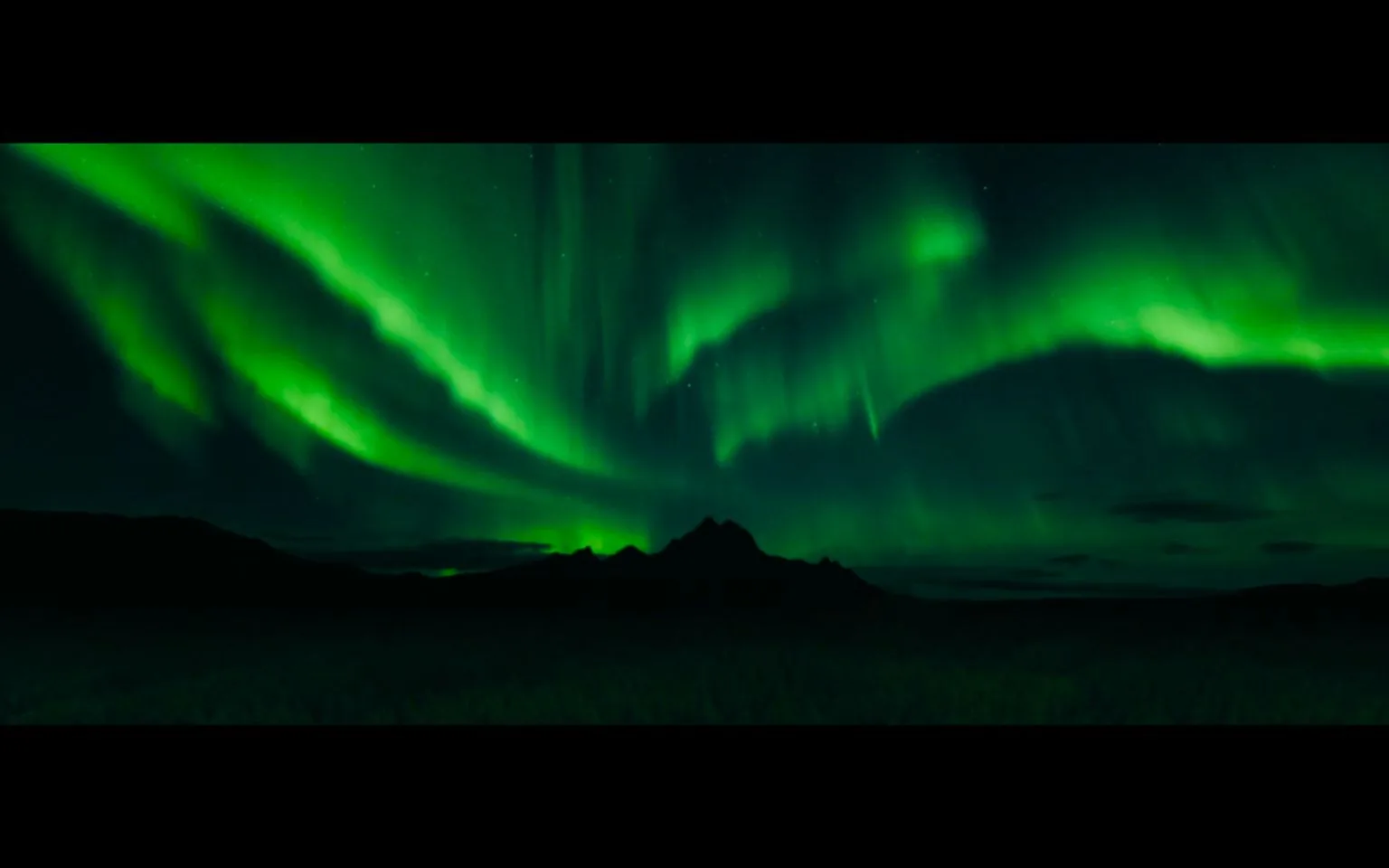 The image captures a stunning natural phenomenon, the Northern Lights, against the backdrop of a dark, silhouetted mountainous landscape. The aurora borealis displays vivid green hues that sweep across the sky in wispy, flowing patterns, creating a captivating visual effect. The scene is set at night, with the vibrant colors of the aurora providing the primary illumination, casting an ethereal glow over the otherwise dark surroundings. The mountainous silhouette in the foreground adds depth and contrast, highlighting the vastness of the sky.
The image is a video frame featuring captions with personal and introspective dialogue, indicating a reflective or emotional scene. The phrases suggest themes of nostalgia, struggle, and introspection, possibly part of a narrative or documentary discussing personal challenges and experiences. The serene yet awe-inspiring visual of the Northern Lights juxtaposes the serious tone of the captions, creating a poignant mood. The lack of any visible branding or text allows the focus to remain on the natural beauty of the aurora and the emotional weight of the narrative.