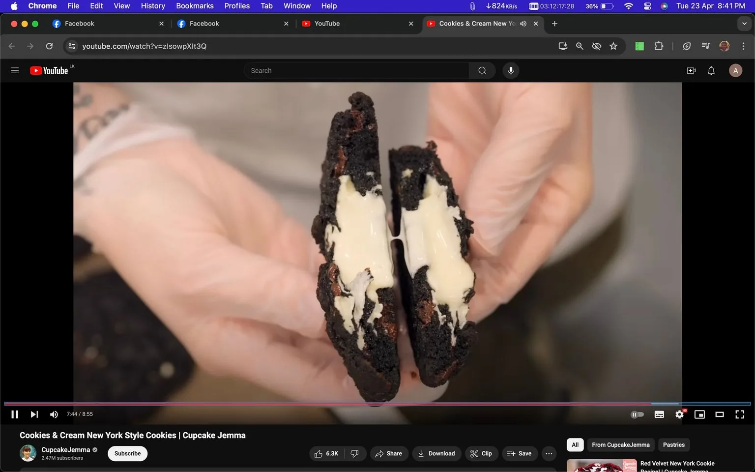The image shows a YouTube video paused at 7:44, titled "Cookies & Cream New York Style Cookies" by Cupcake Jemma. The scene features a close-up shot of a cookie being held with gloved hands. The cookie is split in half, revealing a creamy filling between two dark, possibly chocolate-flavored, cookie halves. The texture of the cookie looks rich and moist, with the cream appearing smooth and slightly glossy. The video is displayed in a browser window, with tabs for Facebook and YouTube visible at the top. The page's interface shows typical YouTube elements such as the like button with 6.3K likes, share, download, and clip options. The background is blurred, keeping the focus on the cookie and the hands holding it. The overall mood is appetizing, likely aimed at viewers interested in baking or dessert recipes. The channel, CupcakeJemma, is highlighted with 2.47 million subscribers, indicating its popularity.
- Title: "Cookies & Cream New York Style Cookies | Cupcake Jemma"
- Channel / profile: "CupcakeJemma"
- Site / app: "YouTube"