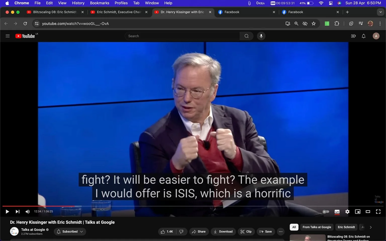 1) Rich description: The image is a video frame from an interview titled "Dr. Henry Kissinger with Eric Schmidt | Talks at Google," hosted on YouTube by the channel "Talks at Google." Eric Schmidt is visible in the frame, seated on a chair and appearing engaged in conversation. He is gesturing with both hands, suggesting an animated discussion. Eric Schmidt is wearing glasses, a white shirt, a red sweater, and a dark blazer, giving him a formal yet approachable appearance. The background features a blue screen, adding a professional ambiance to the setting. Bright studio lighting illuminates the scene, focusing on Eric Schmidt. The video player interface shows the playhead at 12:34 of a 1:06:25 duration, with visible options like play, volume, and full-screen. Subtitles at the bottom read, "fight? It will be easier to fight? The example I would offer is ISIS, which is a horrific," indicating a serious topic of discussion.
2) On-screen text block:
- Title: "Dr. Henry Kissinger with Eric Schmidt | Talks at Google"
- Channel / profile: "Talks at Google"
- Site / app: "YouTube"
- Captions / subtitles: "fight? It will be easier to fight? The example I would offer is ISIS, which is a horrific"