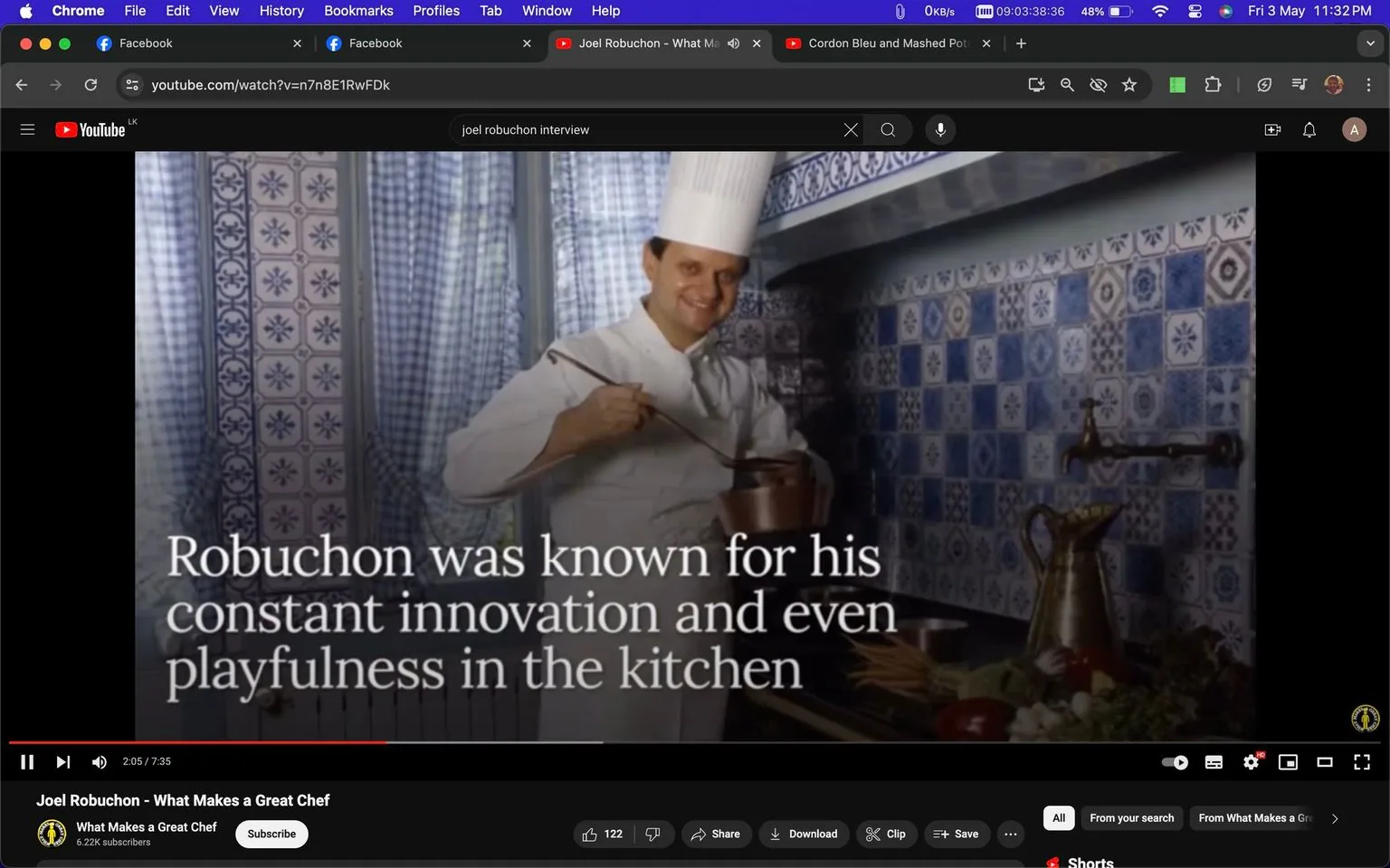 The image is a screenshot taken from a YouTube video titled "Joel Robuchon - What Makes a Great Chef" from the channel "What Makes a Great Chef." In the scene, a chef is smiling while standing in a kitchen, suggesting a playful and innovative atmosphere. The background features blue and white patterned tiles, and there's a decorative brass faucet and a jug visible. The chef is wearing a traditional white chef's uniform and tall hat, holding a copper pot with a ladle, implying he is actively cooking or tasting. The lighting is bright, giving a clean and professional look to the kitchen setting. The on-screen text reads, "Robuchon was known for his constant innovation and even playfulness in the kitchen," highlighting his reputation for creativity and a lighthearted approach in culinary arts.