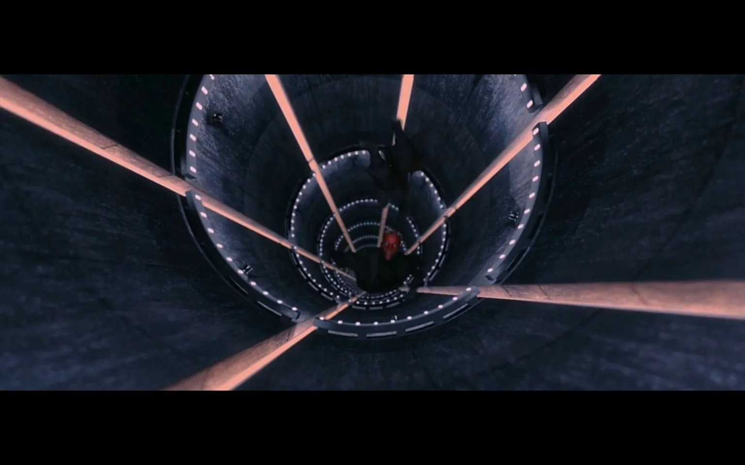 In this dynamic scene from the "Star Wars" franchise, the image captures an intense moment within a large, cylindrical interior. The viewpoint is looking down a seemingly endless shaft, creating a dramatic sense of depth and motion. Two figures are in the center of the frame, appearing to be in mid-air, suggesting they are falling or leaping through the space. The taller figure is dressed in dark clothing, while the other, distinguishable by a red face, is also clad in black, indicating a likely combat or chase scenario. The lighting is dim, with multiple glowing strips lining the walls, enhancing the futuristic and high-tech atmosphere typical of "Star Wars" settings. The scene conveys a sense of tension and urgency, characteristic of the action-packed sequences in the series. The architectural design of the shaft, with its repetitive circular patterns and illuminated edges, adds to the visual impact and the overall immersive experience.