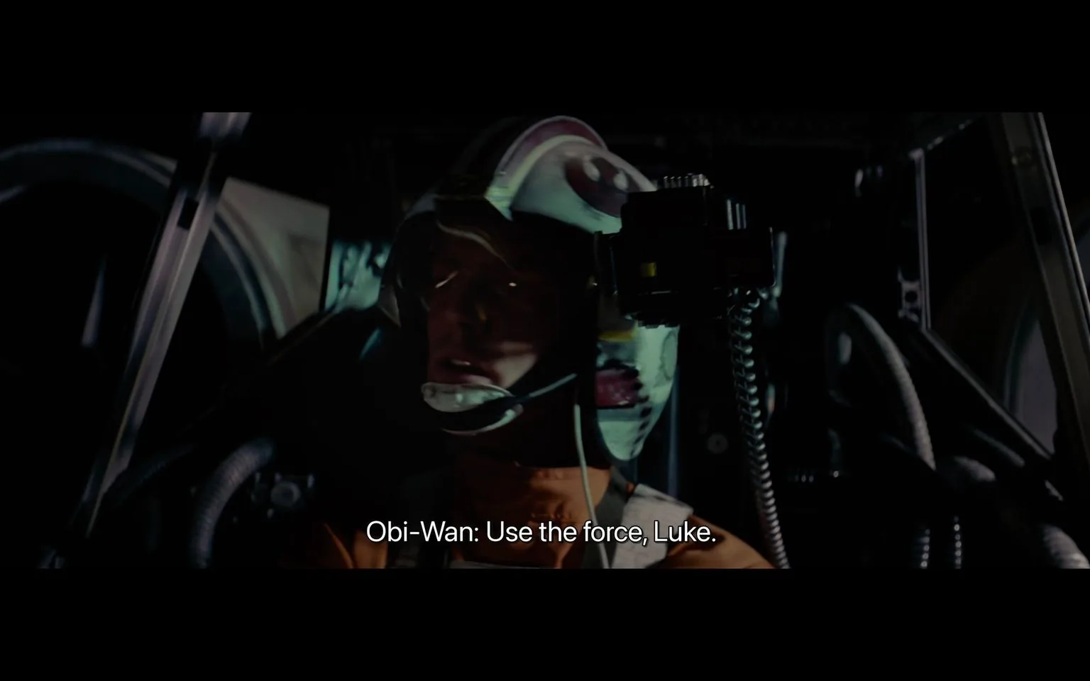 The image is a scene from the film "Star Wars," focusing on a pilot inside a spacecraft cockpit, illuminated by the dim lights of the control panel. The pilot, wearing a white helmet with red markings, is seated and looking intently forward with a serious expression, suggesting focus and determination. The helmet features a transparent visor and communication device, including a microphone positioned near the mouth. In the background, parts of the cockpit, such as curved metallic structures and coiled wires, are visible, adding to the high-tech atmosphere.
The lighting is low, casting shadows across the pilot's face, enhancing the dramatic tension of the scene. The attire consists of a standard flight suit, typical of the pilots in "Star Wars." The subtitle at the bottom reads, "Obi-Wan: Use the force, Luke," indicating a crucial moment where the character is being advised to rely on his instincts and supernatural abilities. The overall mood is intense and suspenseful, capturing a pivotal moment in the story.