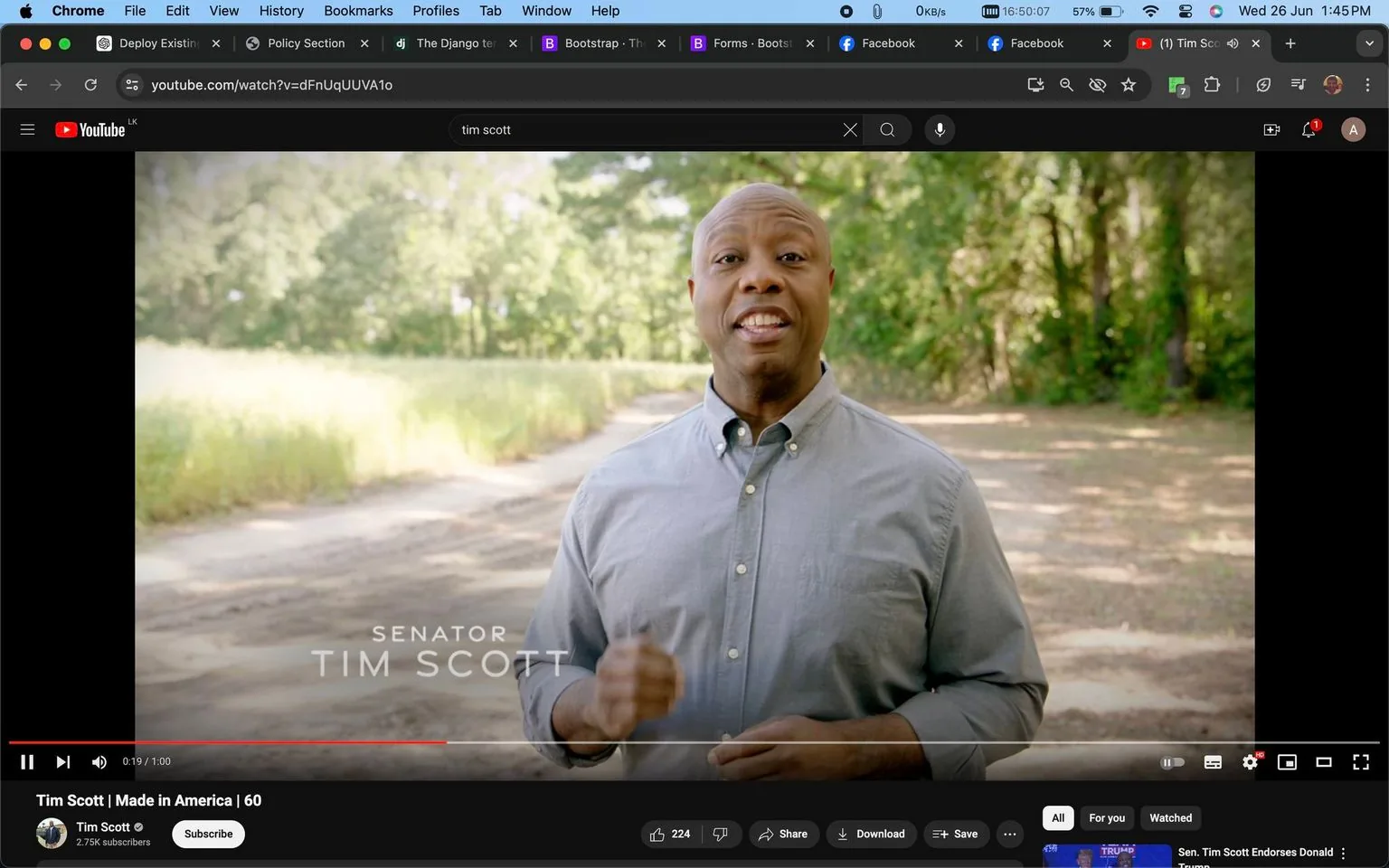 Tim Scott is featured prominently in this YouTube screenshot, taken from a video titled "Tim Scott | Made in America | 60." The video is hosted on his own channel, named "Tim Scott." In the image, Tim Scott is standing outdoors in a natural, wooded area, with sunlight filtering through the trees. He is wearing a light gray button-up shirt, and his demeanor appears confident and engaging as he gestures with one hand, possibly emphasizing a point. The environment is calm and rustic, with a dirt path and green foliage in the background, suggesting a peaceful, rural setting. The screenshot includes on-screen text in the lower left corner identifying him as "Senator Tim Scott," which affirms his political role. The overall mood of the image is professional and approachable, with a focus on conveying a message or addressing an audience directly.