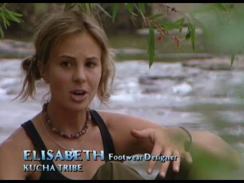 Elisabeth Hasselbeck is featured in this scene from the reality show "Survivor." She is seated outdoors near a body of water, suggesting a natural, serene setting, likely in a tropical location. The background consists of flowing water and lush greenery, contributing to a peaceful and natural atmosphere. Elisabeth is dressed casually in a black tank top and wears a beaded necklace, indicative of the show's rugged, survival-themed context. Her expression appears engaged, perhaps as she shares her thoughts or experiences as part of the Kucha Tribe. The on-screen text identifies her as a "Footwear Designer" and a member of the "Kucha Tribe," providing context about her role and background on the show. The lighting is natural, enhancing the authenticity of the setting. This image captures a moment of personal reflection or conversation, typical of the interview segments in "Survivor."
- Title: "ELISABETH"
- Key OCR Lines: "Footwear Designer", "Kucha Tribe"
