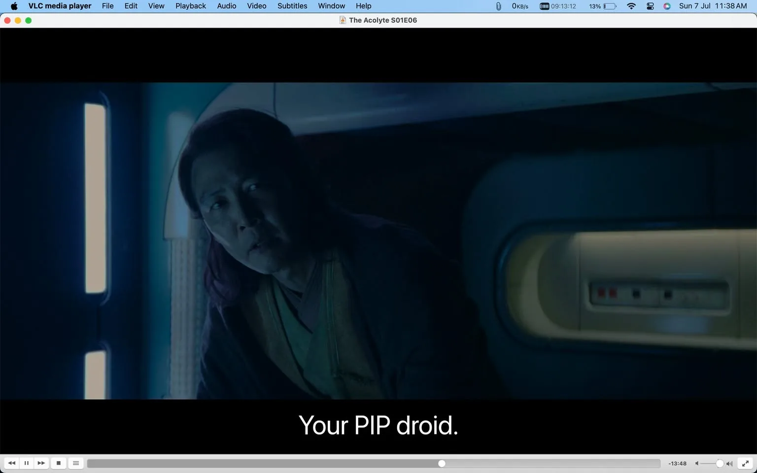 The screenshot is from the show "The Acolyte," specifically episode six of the first season, viewed using VLC media player. The scene is set in a dimly lit, futuristic environment, characterized by cool, blue lighting that casts shadows across the setting. A person, whose identity isn't specified, is partially visible on the left side. They appear to be in a space that resembles a spaceship or a high-tech room. The individual's posture suggests attentiveness or concern as they look towards something off-screen. A horizontal light source and a panel with small colored indicators are visible in the background. The subtitle at the bottom reads, "Your PIP droid," indicating a conversation about a droid, which is likely a piece of technology or character within the narrative. The overall atmosphere is mysterious, typical of a science fiction setting.