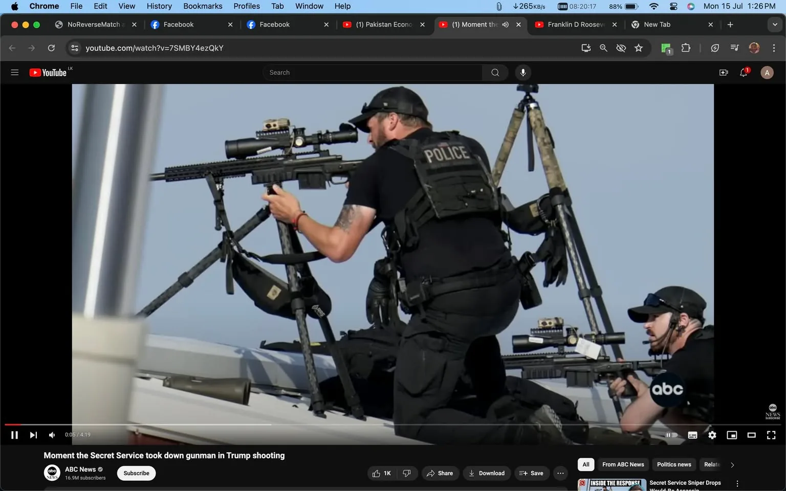 The image is a still from a YouTube video titled "Moment the Secret Service took down gunman in Trump shooting," published by ABC News. The scene captures two individuals in tactical police gear positioned on a rooftop or elevated platform. They are both wearing black caps and tactical vests labeled "POLICE," with one of them aiming a sniper rifle mounted on a tripod. The other individual is also handling a firearm, possibly providing support or secondary coverage. The setting appears to be outdoors, likely during daylight, given the clear sky in the background. The focus is on the readiness and positioning of the officers, indicating a high-alert security situation. The image represents a moment of intense focus and preparation, with the officers' postures showing vigilance and professionalism. The screenshot is presented within a YouTube interface, with visible elements like the video link and control options, giving context to the narrative of a high-stakes security incident involving a potential gunman during an event with Donald Trump.