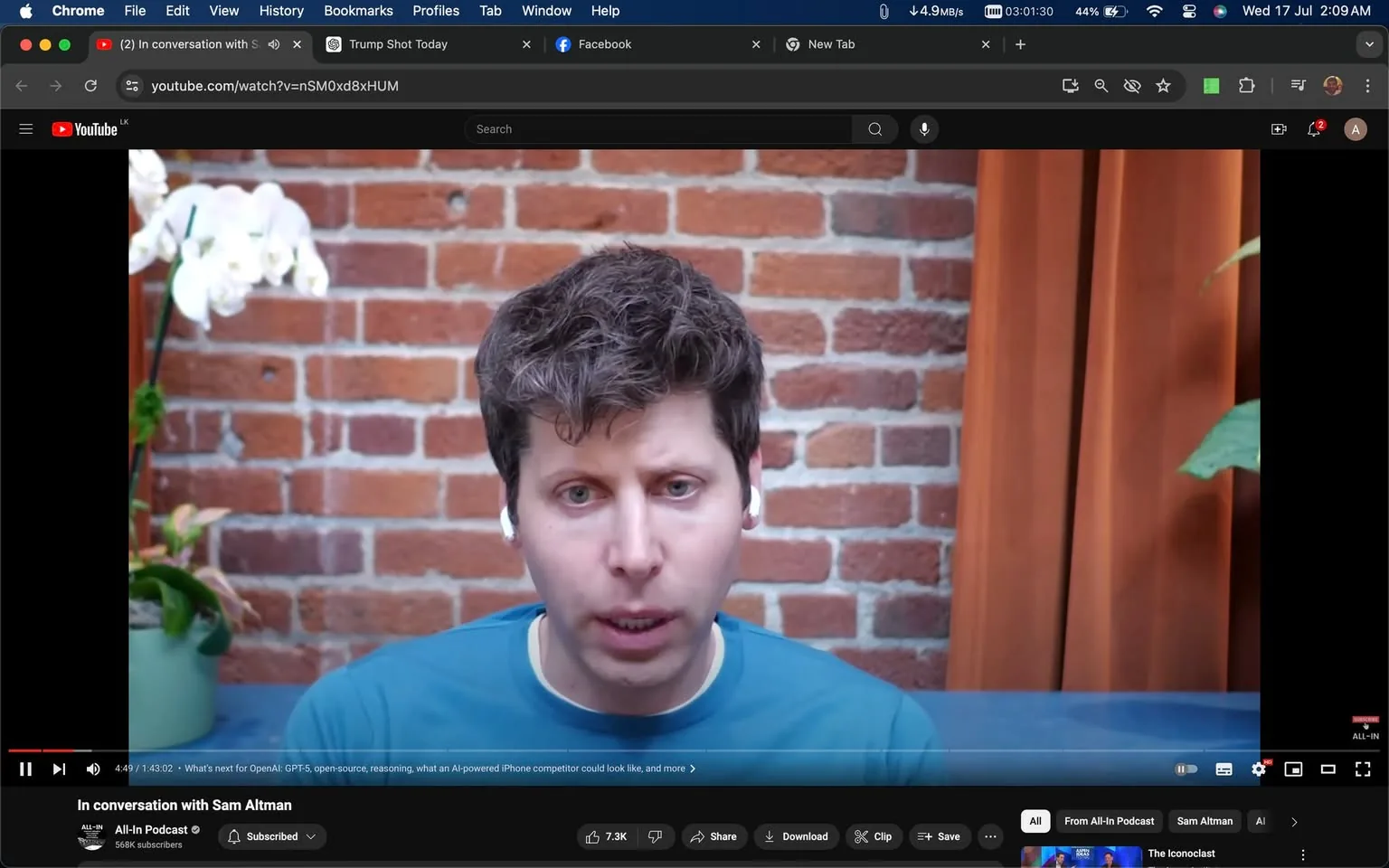 The image is a frame from a YouTube video titled "In conversation with Sam Altman," hosted on the "All-In Podcast" channel. Sam Altman is prominently featured in the center of the frame, wearing a blue shirt and white earbuds. The setting appears to be indoors, with a brick wall providing a rustic backdrop. To the left, there is a white orchid in a pot, adding a touch of nature to the scene. An orange curtain is partially visible on the right side, contributing warmth to the overall ambiance. Sam Altman's expression is attentive, suggesting engagement in a thoughtful discussion. The lighting is soft and natural, highlighting his features without casting harsh shadows. The video seems to be focused on topics related to AI and technology, as indicated by the context and channel profile.
- Title: "In conversation with Sam Altman"
- Channel / profile: "All-In Podcast"
- Site / app: "YouTube"