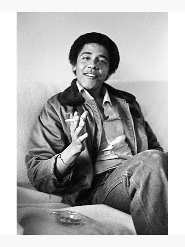 Barack Obama is depicted in this black-and-white photograph, which exudes a relaxed and candid atmosphere. He is seated on a light-colored sofa, leaning back comfortably while holding a cigarette in his right hand. His expression is laid-back and cheerful, suggesting a moment of casual conversation or reflection. Obama is dressed in a casual outfit, wearing a collared shirt beneath a jacket with a fur-like collar, and denim jeans. His hair is styled in a natural afro, typical of the era. The lighting is soft and natural, illuminating the scene without harsh shadows, contributing to the intimate and informal setting. An ashtray is visible on the sofa beside him, reinforcing the casual nature of the scene. The overall composition, with its simple background and focus on Obama, creates an authentic snapshot of a moment in time.
