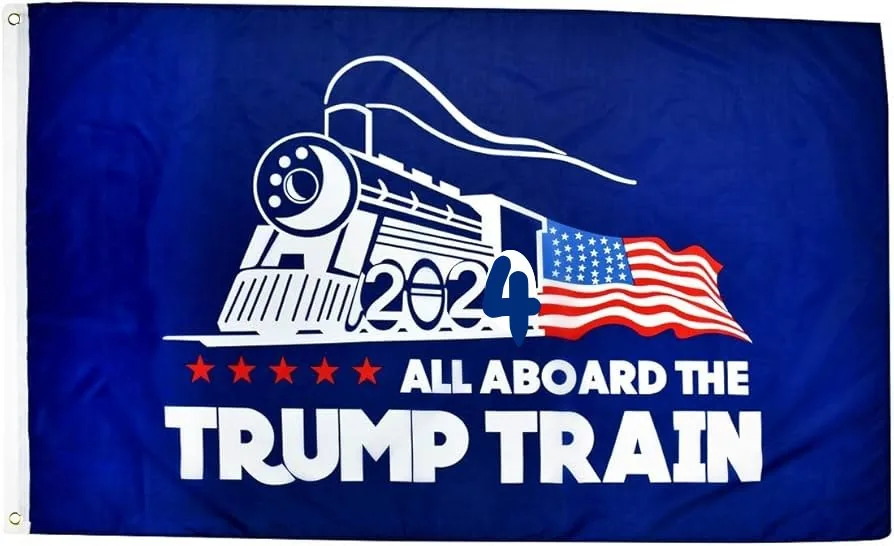 The image features a flag with a political theme. It is predominantly blue and has a stylized white illustration of a train on the left side. The train is facing to the right, and the number "2024" is prominently displayed on its side, indicating a campaign reference for that year. Behind the train, there is an American flag design, adding a patriotic element to the image. Below the train, in bold white text, are the words "ALL ABOARD THE TRUMP TRAIN," which suggest support for Donald Trump's political campaign. The flag includes five red stars, further emphasizing the political theme. The overall color scheme is red, white, and blue, aligning with typical American patriotic colors.