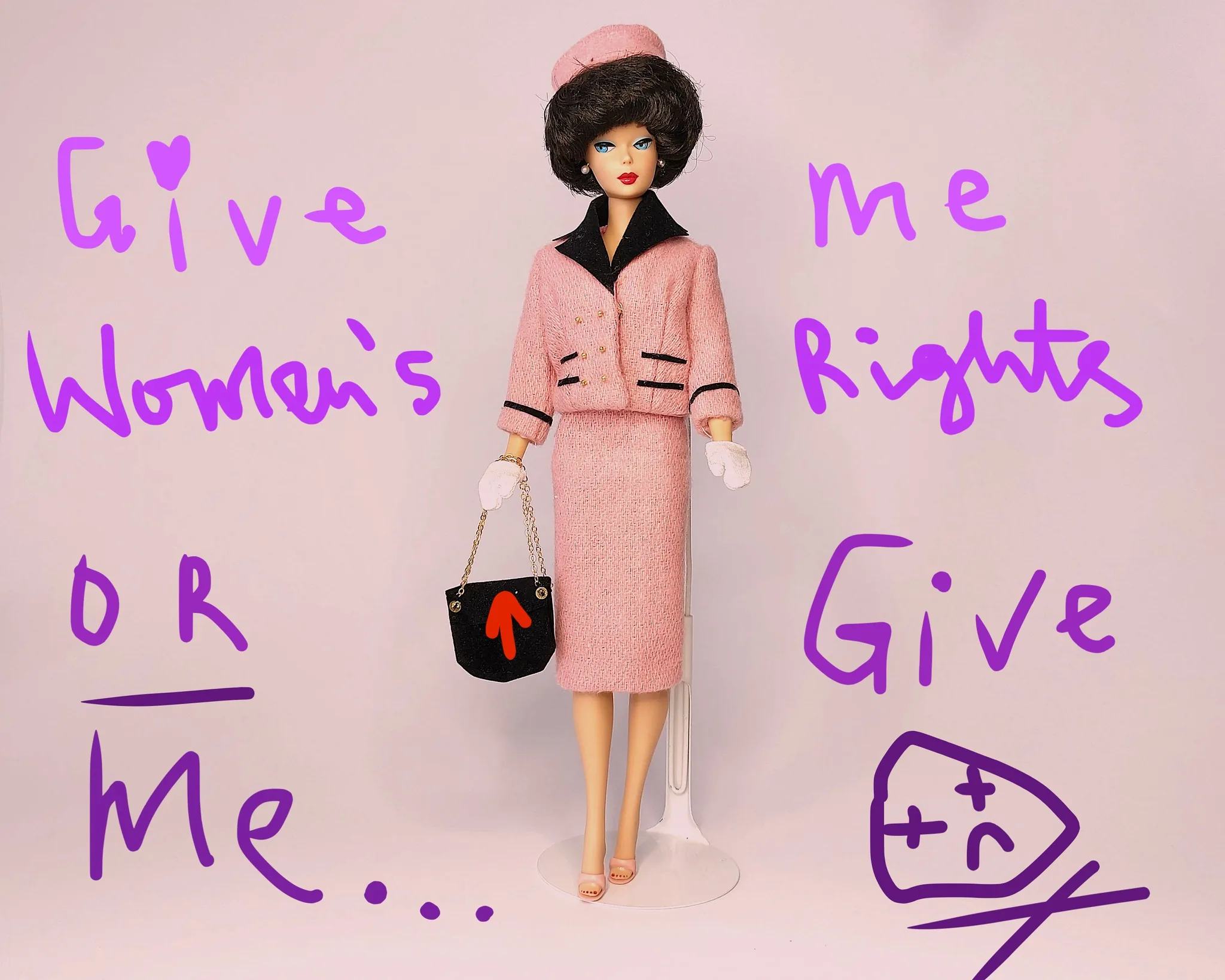 This image features a Barbie doll dressed in a pink ensemble reminiscent of a 1960s fashion style. She wears a tailored suit with a matching hat, black accents, and pink gloves. Her stylish handbag has a gold chain and displays a red arrow. The background is a soft pink, complementing her outfit. Overlaying the image is handwritten text in purple, stating: "Give Women's Rights OR Give Me...". The message appears to advocate for women's rights, employing humor and a sense of urgency with a playful illustration of a sad face and X eyes at the bottom right. The overall mood combines fashion with activism, using the iconic Barbie figure to convey a message of empowerment and social change.