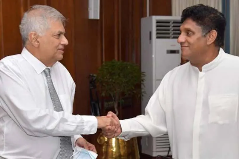 1) Rich description: The image shows an indoor meeting between Ranil Wickremasinghe and Sajith Premadasa. They are engaged in a formal handshake, suggesting a cordial or diplomatic encounter. Ranil Wickremasinghe, on the left, is wearing a white dress shirt with a tie, holding a face mask in his left hand. Sajith Premadasa, on the right, is dressed in a traditional white outfit, which contrasts with the modern attire of Wickremasinghe. Both men appear to be smiling slightly, indicating a friendly or formal exchange. The background features wood-paneled walls and a potted plant, creating a formal and official ambiance. An air conditioning unit is visible, adding to the office-like setting. The lighting is bright, highlighting the subjects and their expressions clearly. The image captures a moment of political or formal significance, underscoring a gesture of mutual respect or agreement.
2) On-screen text block:
- Title: "unknown"
- Channel / profile: "unknown"
- Site / app: "unknown"