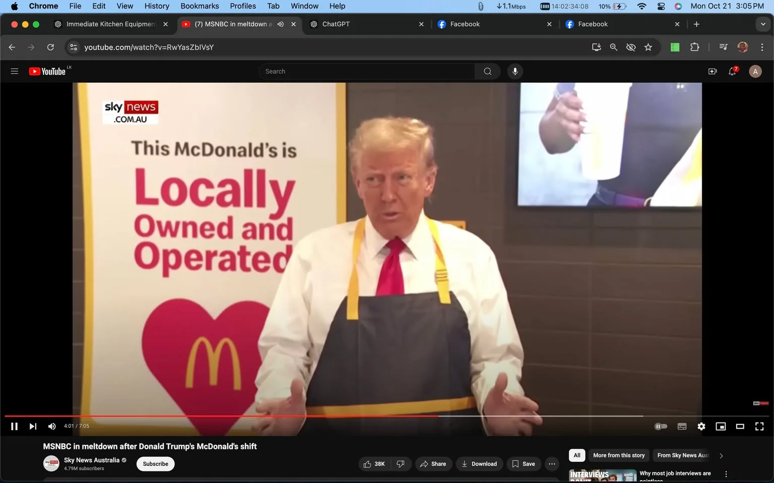 Donald Trump is shown inside a McDonald's restaurant, wearing a white shirt and a red tie, complemented by a gray apron with yellow straps. He is visibly speaking or making a gesture with his hands, suggesting he might be addressing an audience or participating in an event. Behind him, a sign reads "This McDonald's is Locally Owned and Operated" with the McDonald's logo prominently displayed. The setting appears warm and well-lit, typical of a fast-food restaurant environment. A television screen is partially visible on the right side, showing a person holding a drink cup. The video is a frame from YouTube titled "MSNBC in meltdown after Donald Trump's McDonald's shift," featured on the "Sky News Australia" channel, indicating the video's focus on Donald Trump's visit or activity at the restaurant. The overall mood is formal yet approachable, as he is dressed in a business-like manner while participating in a casual setting.