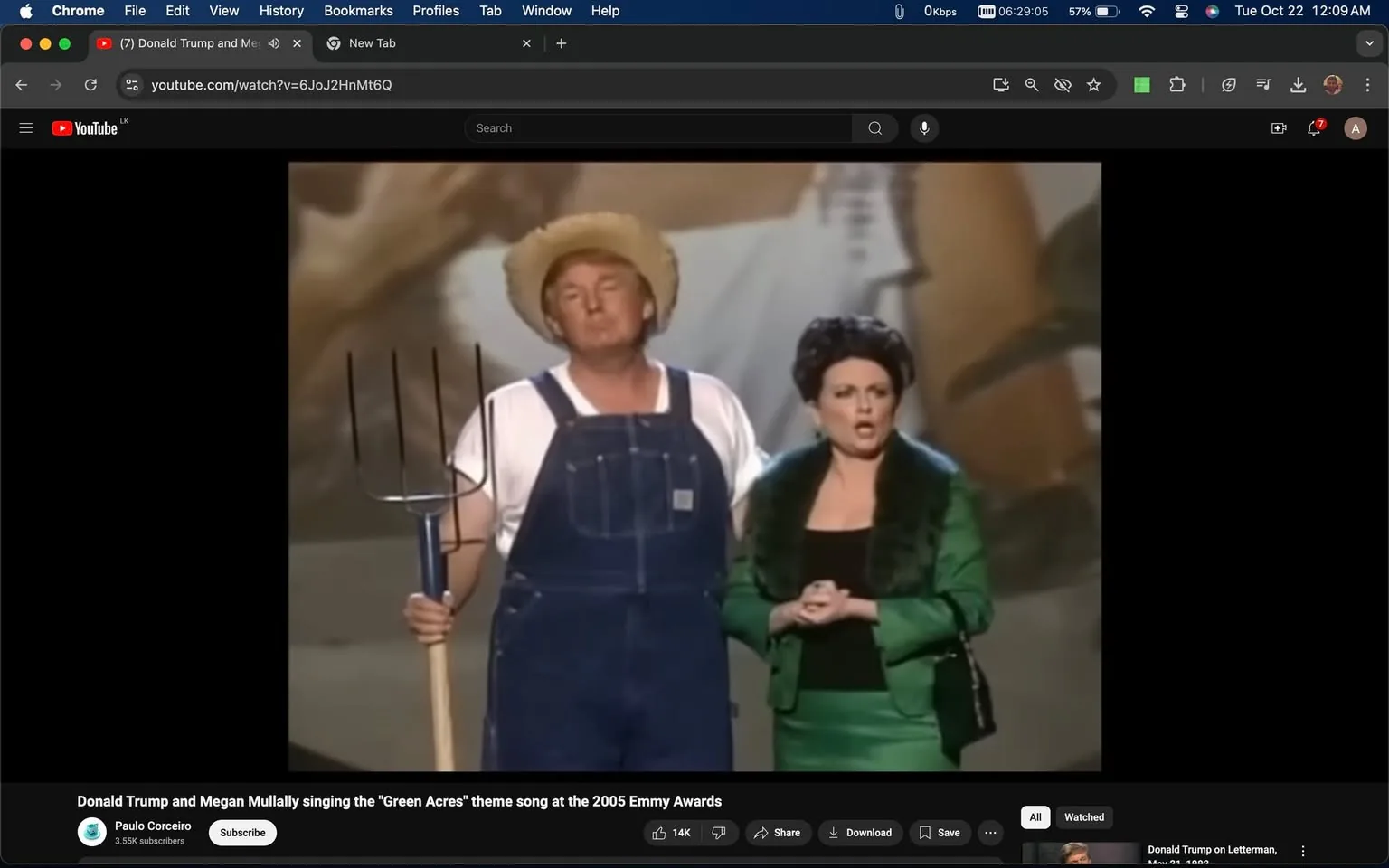 The image is a screenshot from a YouTube video featuring Donald Trump and Megan Mullally performing at the 2005 Emmy Awards. They are singing the theme song from "Green Acres." Donald Trump is dressed in a humorous farmer costume, wearing a straw hat, white undershirt, and denim overalls, while holding a pitchfork. Megan Mullally is beside him, adorned in a striking green outfit with a fur-lined collar, exuding a glamorous contrast to Trump's rural get-up. The background suggests a stage setting, likely designed to echo the rustic theme of "Green Acres." The image captures a lighthearted moment with both individuals appearing animated and engaged in the performance. The video is hosted on YouTube, uploaded by the channel Paulo Corceiro, and the video's title clearly outlines the context of the scene. The lighting is bright, typical of stage performances, emphasizing both performers in the center of the frame.
- Title: "Donald Trump and Megan Mullally singing the \"Green Acres\" theme song at the 2005 Emmy Awards"
- Channel / profile: "Paulo Corceiro"
- Site / app: "YouTube"