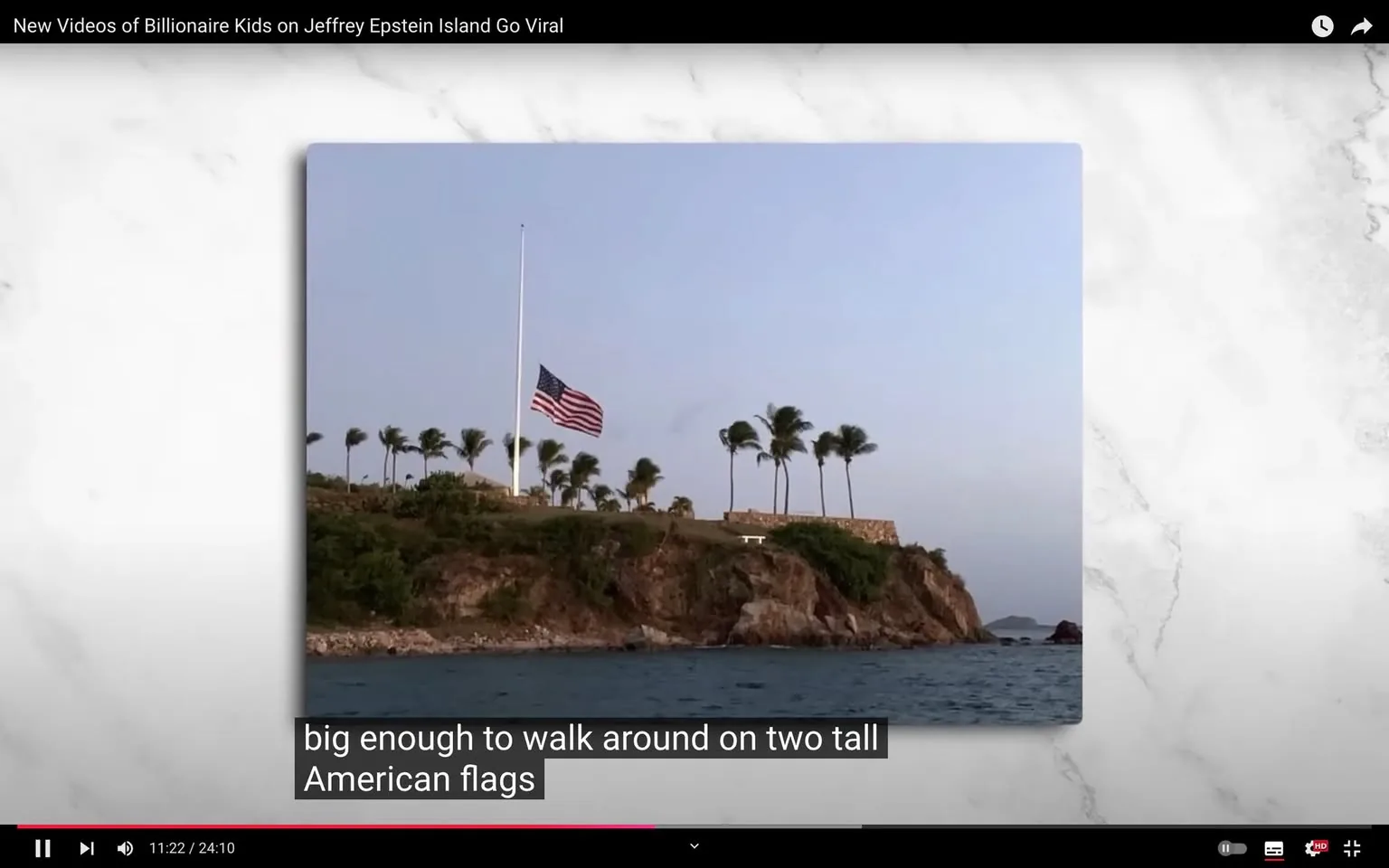 The image depicts a video frame showing a scenic view of an island. In the foreground, there is a body of water with gentle waves, suggesting a coastal location. The background reveals a rocky shoreline topped with lush greenery and several tall palm trees swaying in the breeze. A prominent feature is the American flag, flying at half-staff on a tall flagpole, standing out against the clear blue sky. The lighting suggests either early morning or late afternoon, casting a soft, warm glow over the scene. The composition conveys a sense of isolation and tranquility, typical of a private island setting. The frame is from a video titled "New Videos of Billionaire Kids on Jeffrey Epstein Island Go Viral," indicating a connection to the controversial figure Jeffrey Epstein. The text overlay at the bottom reads, "big enough to walk around on two tall American flags," adding context to the visual narrative.
- Title: "New Videos of Billionaire Kids on Jeffrey Epstein Island Go Viral"
- Captions / subtitles: "big enough to walk around on two tall American flags"