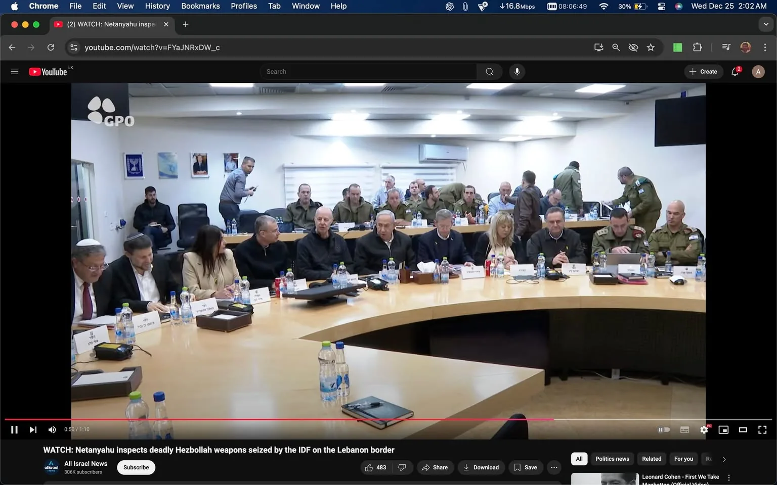 1) The image is a screenshot from a YouTube video titled "WATCH: Netanyahu inspects deadly Hezbollah weapons seized by the IDF on the Lebanon border," hosted on the channel All Israel News. The scene captures a meeting in a well-lit conference room with a large, U-shaped table. Several individuals are seated around the table, including both civilians and military personnel, indicating a formal discussion or briefing. The individuals are dressed in a mix of business and military attire, with some wearing suits and others in military uniforms. Bottles of water and microphones are placed on the table, suggesting a formal setup for a meeting. There are nameplates in front of each person, displaying names in a language that appears to be Hebrew. The room is equipped with overhead lighting and air conditioning, adding to the professional environment. In the background, a few people are either standing or seated, possibly taking notes or preparing documents. The atmosphere appears serious and focused, likely due to the sensitive nature of the meeting topic concerning Hezbollah weapons and regional security.

2) On-screen text block:
- Title: "WATCH: Netanyahu inspects deadly Hezbollah weapons seized by the IDF on the Lebanon border"
- Channel / profile: "All Israel News"
- Site / app: "YouTube"