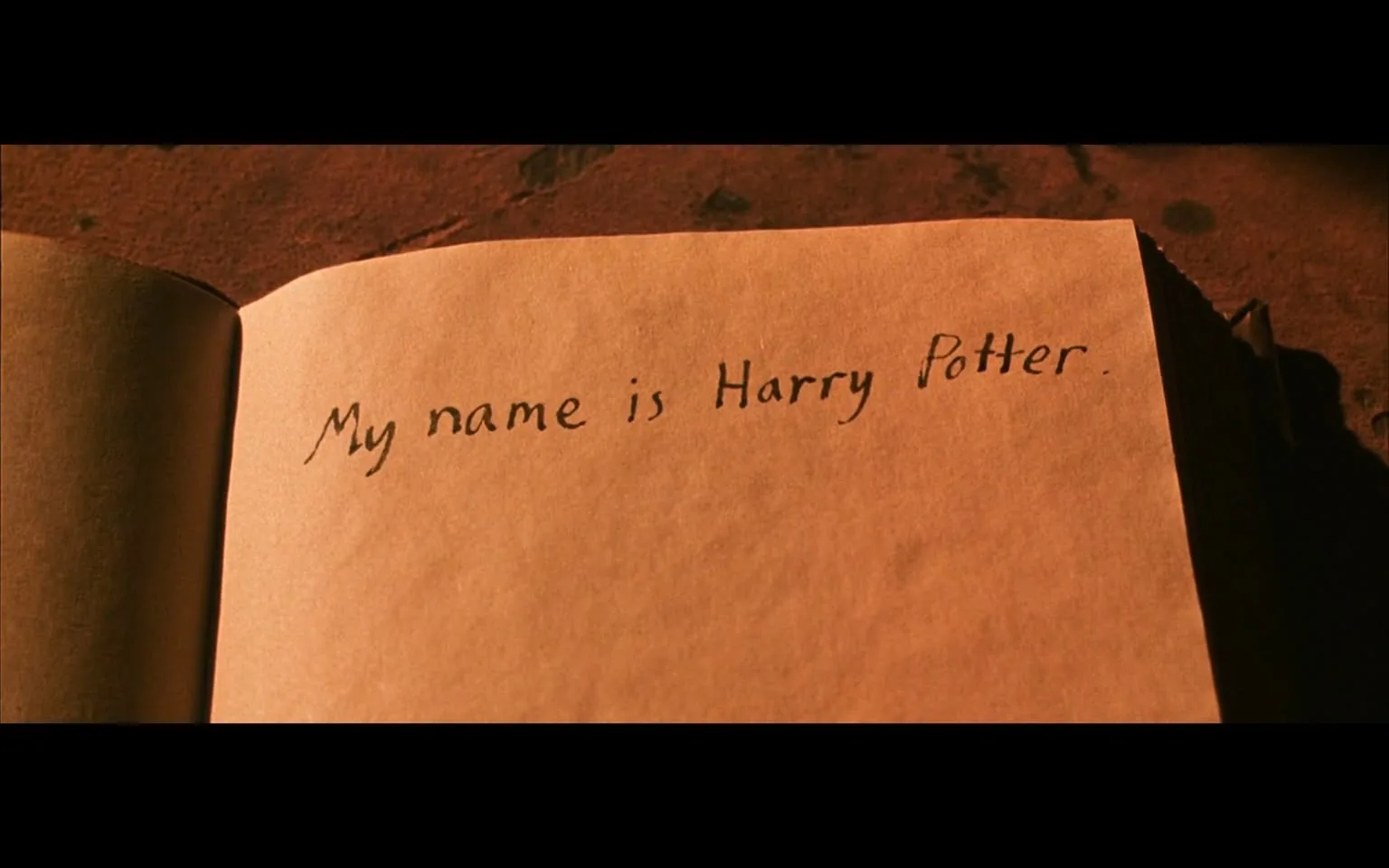 The image is a close-up of an open book page, featuring handwritten text that reads, "My name is Harry Potter." The page is parchment-colored, giving it an aged, magical appearance. The text is written in black ink, with a simple, straightforward handwriting style that suggests an informal, personal note. This scene is likely from the "Harry Potter" series, capturing a moment where the character Harry Potter is interacting with a magical book or diary.

The lighting is warm and soft, casting gentle shadows across the page and enhancing the mystical atmosphere associated with the "Harry Potter" universe. The background is subtly textured, possibly a wooden table, adding to the old-world charm of the setting. This image evokes curiosity and nostalgia, characteristic of the magical and mysterious elements found throughout the "Harry Potter" stories.