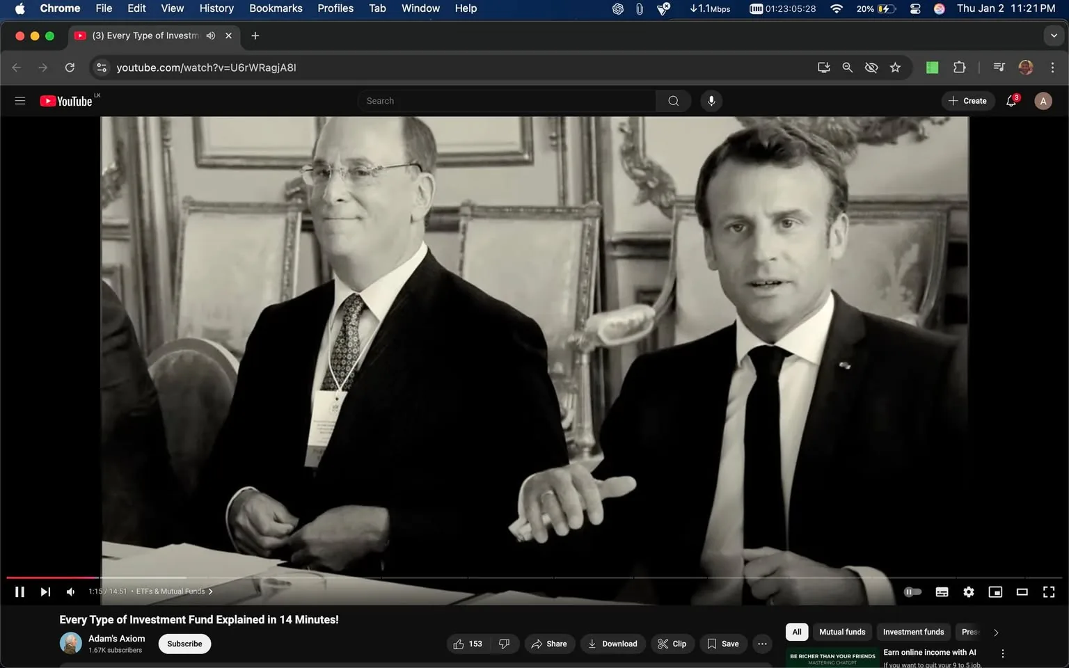 In a formal indoor setting, two men are seated at a table, engaged in discussion. The man on the right, dressed in a black suit and tie, gestures with his hand as he speaks, displaying a serious expression. He has short, neatly styled hair. The man on the left, wearing glasses and a suit, appears to be listening attentively, with a slight smile on his face. Both individuals are surrounded by ornate decor, including framed artwork and elegant furniture in the background. The atmosphere suggests a professional meeting or conference. There are no visible brands or logos in the image.