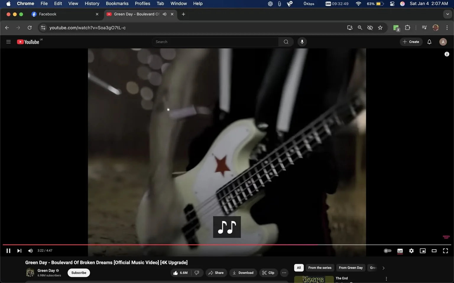 The image captures a close-up view of a bass guitar, prominently featuring a red star design on its body. The guitar is being played by an unidentified individual, whose arm is partially visible, suggesting a dynamic performance. The background is blurred, creating a sense of movement and energy typical of a music video setting. The video is titled "Green Day - Boulevard Of Broken Dreams," indicating that this scene is part of a performance by the band Green Day. The overall atmosphere appears to be lively and engaging, characteristic of a rock music environment.