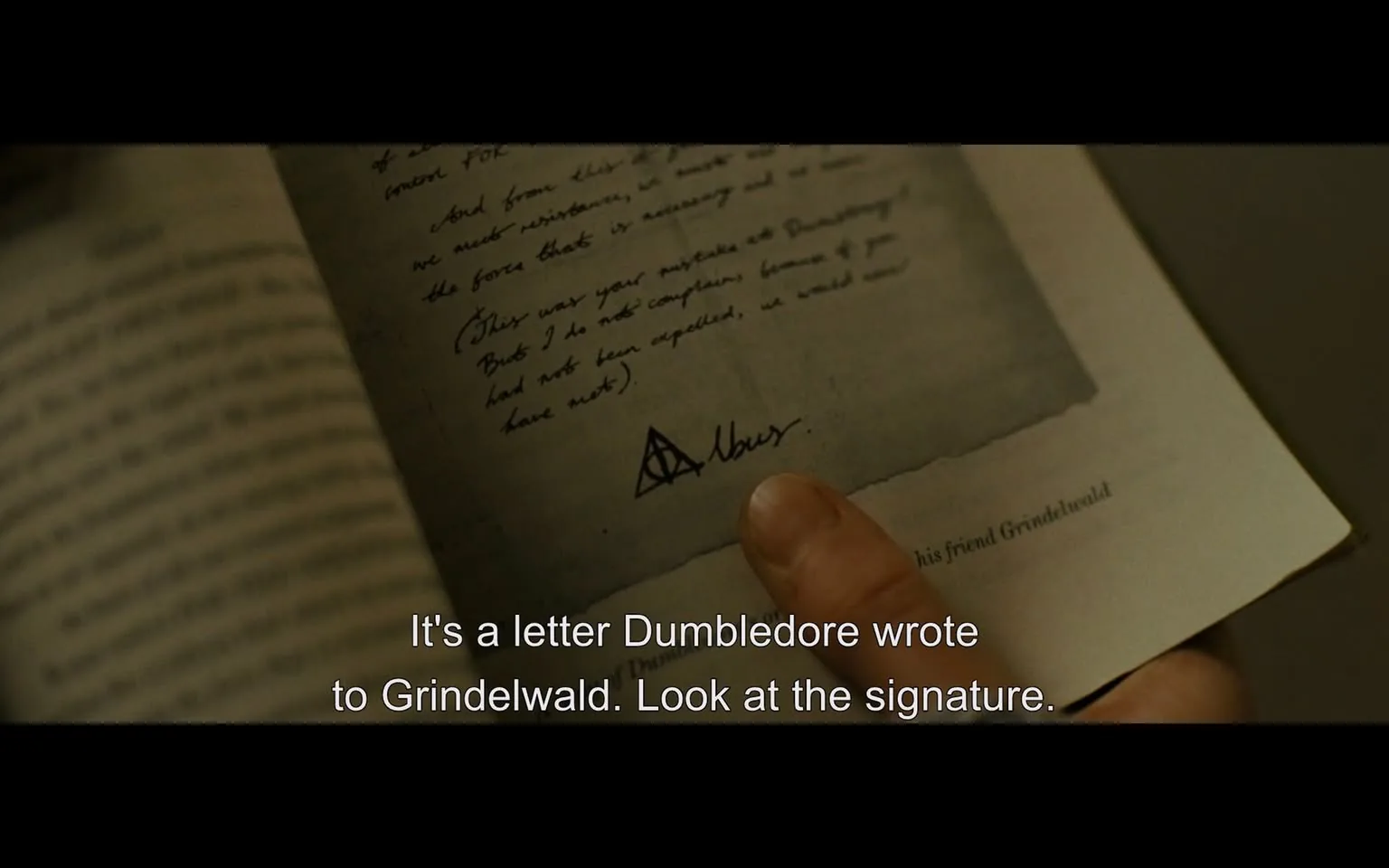 In the image, a hand is pointing to a letter that appears to be written on aged paper, suggesting a historical or fictional context. The letter contains handwritten text, with phrases that indicate a correspondence between two characters, specifically mentioning Dumbledore and Grindelwald. The signature at the bottom reads "Albus," accompanied by a symbol resembling a triangle with a circle and a line, which is often associated with the "Deathly Hallows" from the Harry Potter series. The background shows a book with pages that are slightly blurred, indicating that the focus is on the letter itself. The overall setting appears to be indoors, likely in a study or library environment.