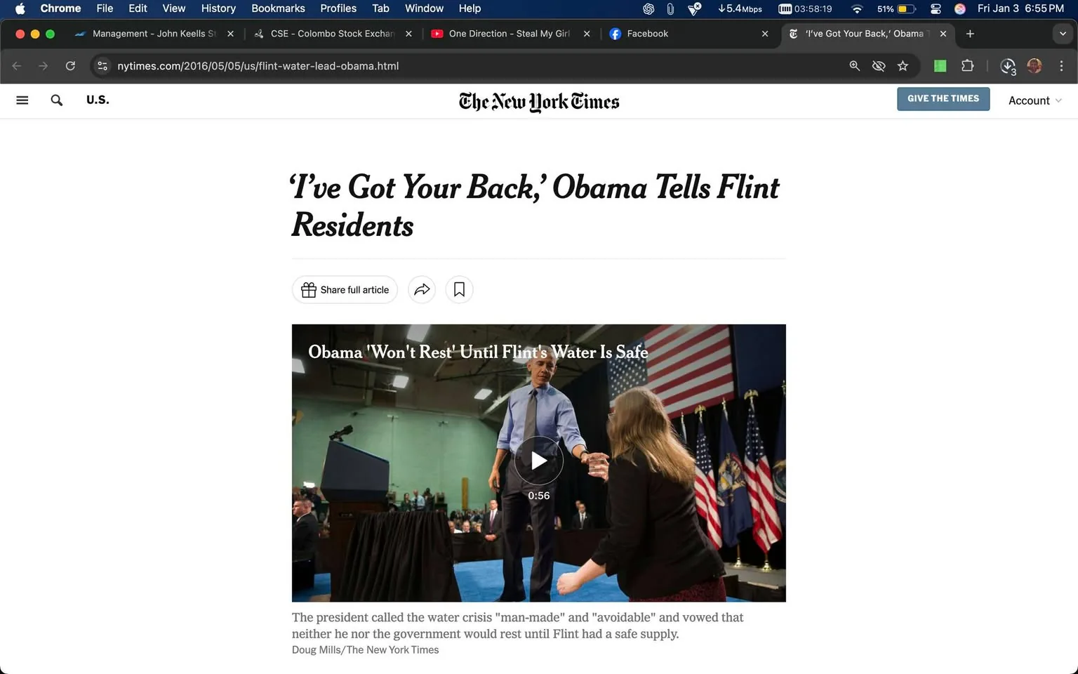In the image, a public figure is seen interacting with a woman during an event focused on the Flint water crisis. The setting appears to be indoors, likely in a community center or similar venue, with a backdrop featuring multiple American flags. The public figure is dressed in a light blue shirt and dark pants, while the woman is wearing a black jacket and patterned skirt. The atmosphere suggests a serious discussion, as the public figure gestures while speaking, indicating a commitment to addressing the water safety issues in Flint. The text overlay states, "Obama 'Won't Rest' Until Flint's Water Is Safe," emphasizing the urgency of the situation.