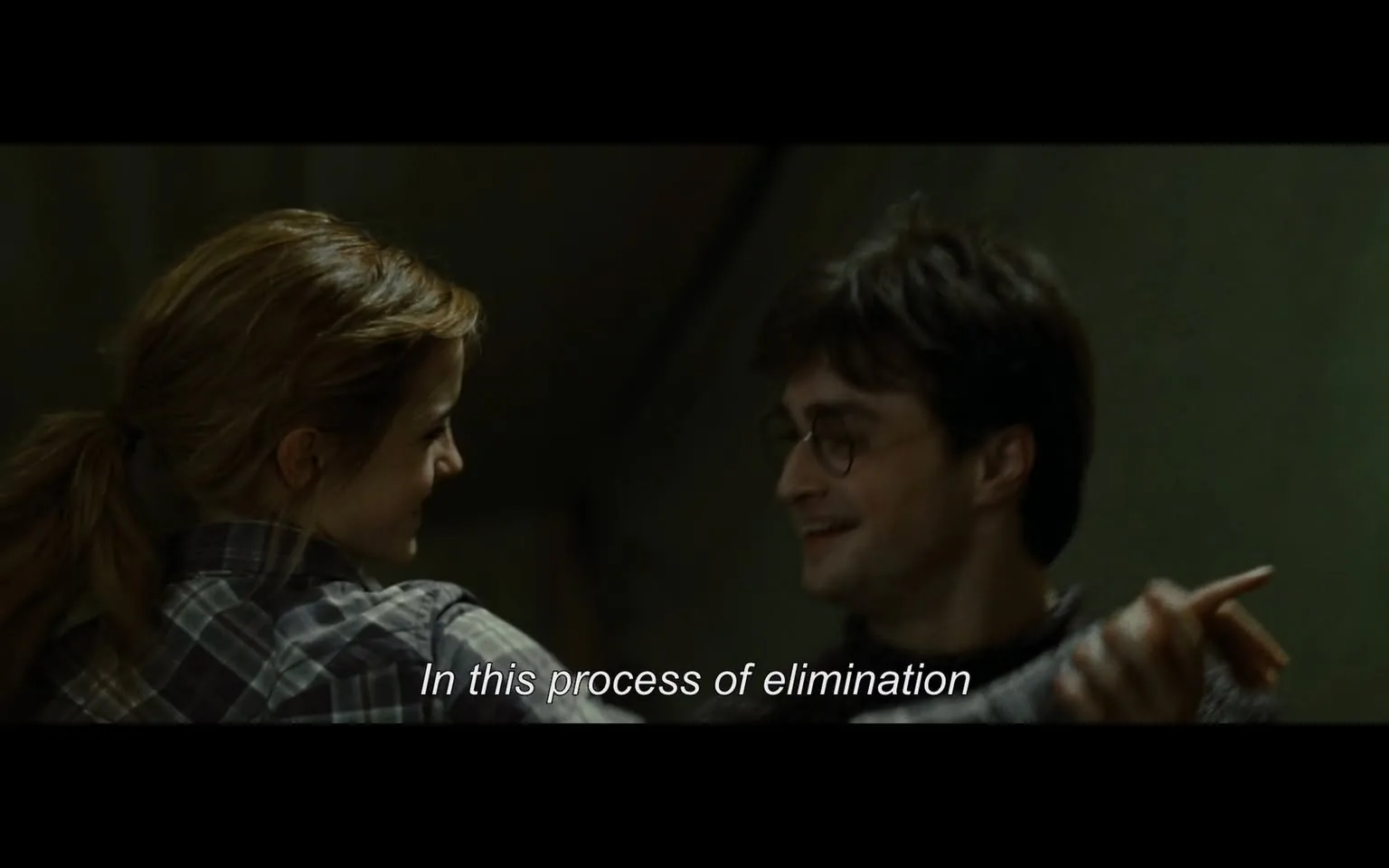 In the scene, two characters are sharing a joyful moment, smiling at each other while engaged in conversation. One character has long, light brown hair tied back and is wearing a plaid shirt, while the other has short, dark hair and is wearing glasses. The setting appears to be indoors, with a somewhat dimly lit background that suggests a casual or intimate atmosphere. The dialogue displayed on the screen reads, "In this process of elimination," indicating a playful or strategic discussion between them. Their expressions convey warmth and camaraderie, enhancing the light-hearted tone of the interaction.