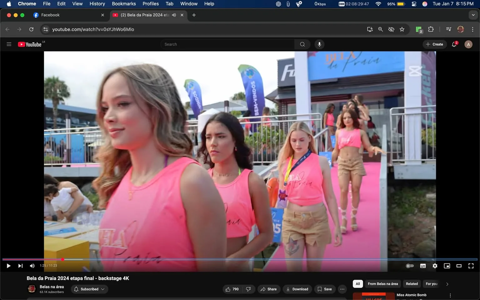 In a vibrant outdoor setting, several individuals are participating in a fashion event, likely a pageant or modeling showcase. The main focus is on four women walking along a pink runway, dressed in matching bright pink tops with the text "Bela da Praia" visible. The women appear to be in their late teens to early twenties, showcasing a range of hairstyles and expressions. The background features banners and signage, indicating a festive atmosphere. The event seems to be taking place during the day, with natural light illuminating the scene. The presence of a crowd and additional participants can be seen in the background, contributing to the lively ambiance of the event.