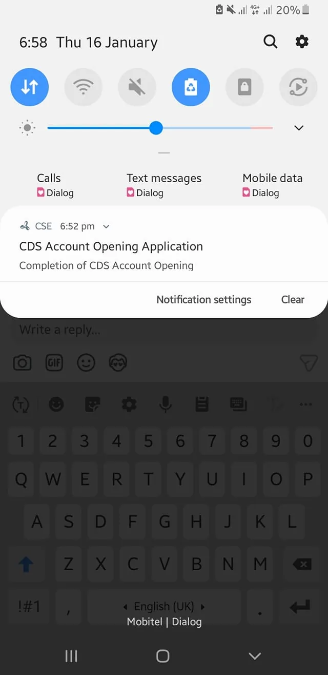 The image features a mobile phone screen displaying a notification at 6:58 PM on Thursday, January 16. The notification, received at 6:52 PM, is from "CSE" and pertains to a "CDS Account Opening Application," indicating the completion of the account opening process. The phone's status bar shows connectivity icons, including signal strength and battery percentage, with the mobile network provider identified as "Dialog." Below the notification, there is a text input area with a keyboard visible, suggesting the user may be preparing to respond or interact with the notification. The overall setting appears to be indoors, likely in a personal or office environment.