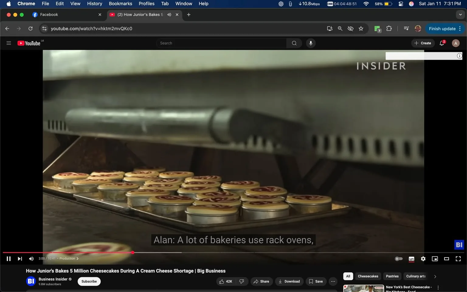 In the image, a tray filled with small cheesecake tins is positioned inside a rack oven. The tins are neatly arranged, showcasing their round shape and a decorative top, likely indicating a flavor or brand. The setting appears to be a bakery, with the oven's metallic interior visible in the background. The text overlay includes a quote from someone named Alan, discussing the use of rack ovens in bakeries. The overall atmosphere suggests a busy baking environment, likely focused on producing a large quantity of cheesecakes.