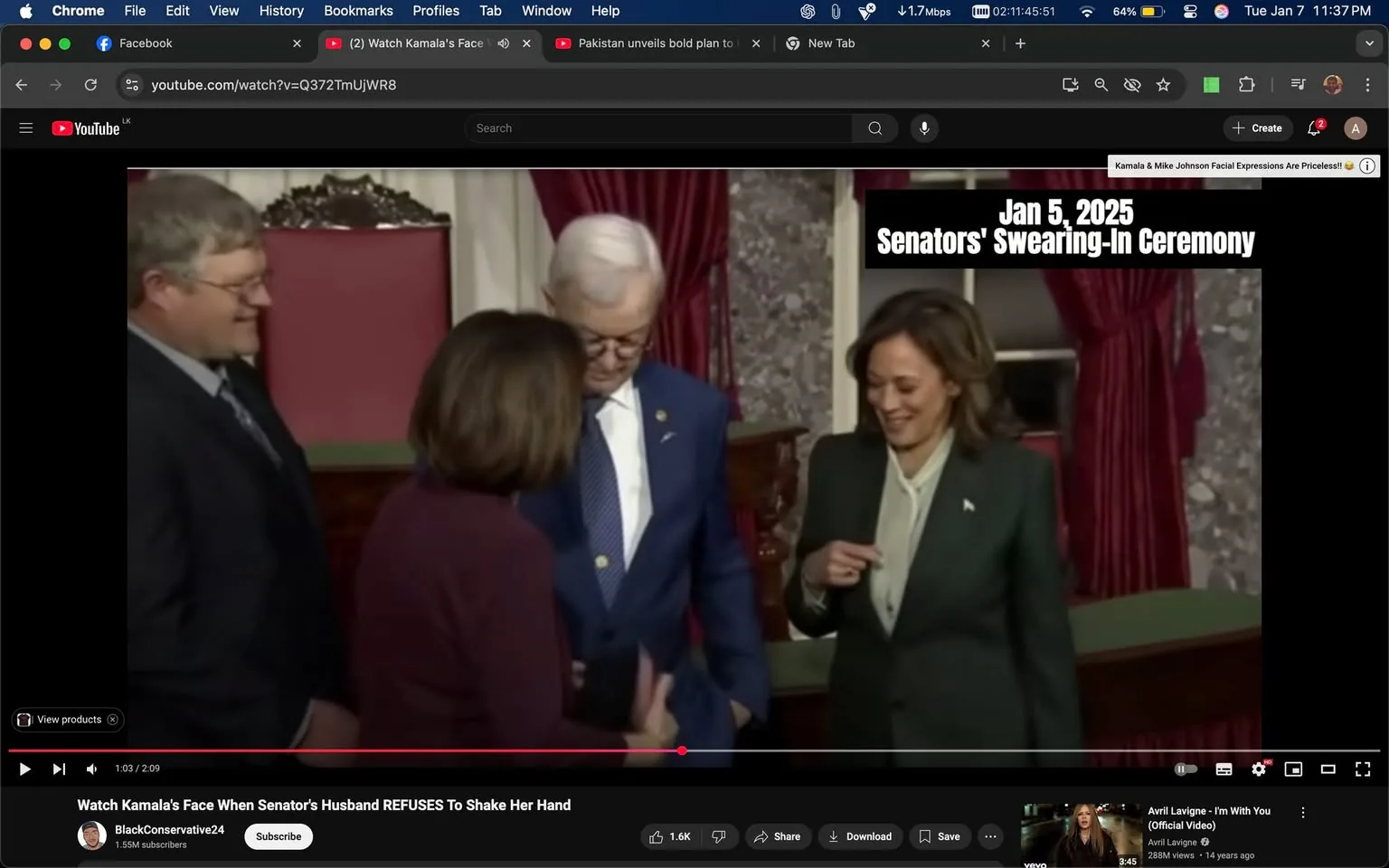 The image captures a moment during a formal event, likely a swearing-in ceremony, as indicated by the text overlay. Four individuals are present, with two men and two women visible. One woman, dressed in a green suit, appears to be smiling and engaging with the others. The man beside her is wearing a blue suit and glasses, seemingly focused on a document or item being held by another woman, who is dressed in a maroon outfit. The setting is indoors, characterized by ornate decor, including red curtains and a decorative backdrop. The atmosphere suggests a significant political occasion, with the individuals likely involved in governmental roles.