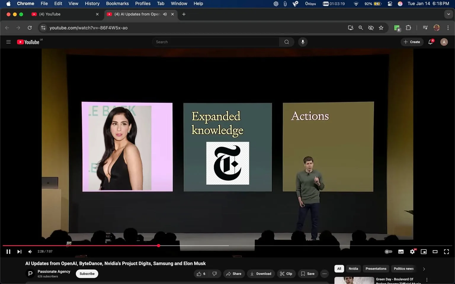 In a presentation setting, a speaker stands on stage, gesturing as they discuss topics related to "Expanded knowledge" and "Actions." The backdrop features three main sections: on the left, there is an image of an unidentified adult woman in a black dress against a pink background; the center displays the New York Times logo; and the right section is labeled "Actions" on a green background. The audience is partially visible in the foreground, and the overall atmosphere suggests a tech or media event. The speaker is dressed casually in a green sweater and appears engaged in the presentation.