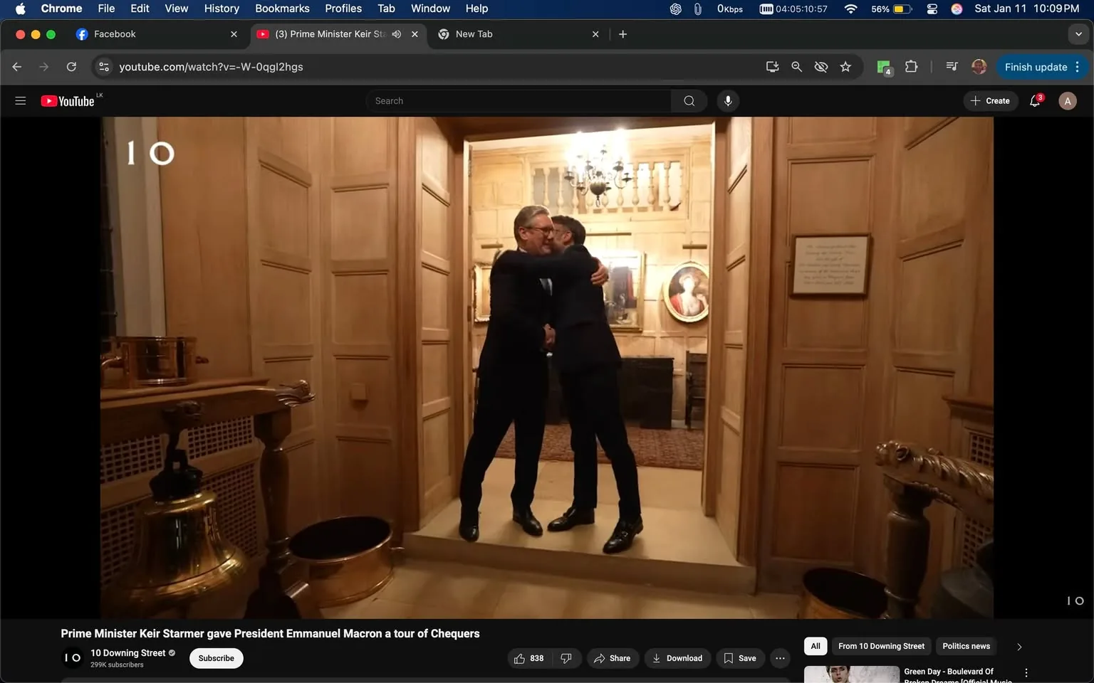 In the image, two individuals are engaged in a warm embrace, indicating a friendly or celebratory moment. They are dressed in formal attire, with one wearing a dark suit and the other also in a similar outfit. The setting appears to be indoors, characterized by wooden paneling and elegant decor, including a chandelier and framed artwork on the walls. The floor is covered with a patterned rug, and there are decorative elements like a bell and a basin visible in the foreground. The atmosphere suggests a significant or formal occasion, possibly related to a political or diplomatic event, as indicated by the surrounding context.