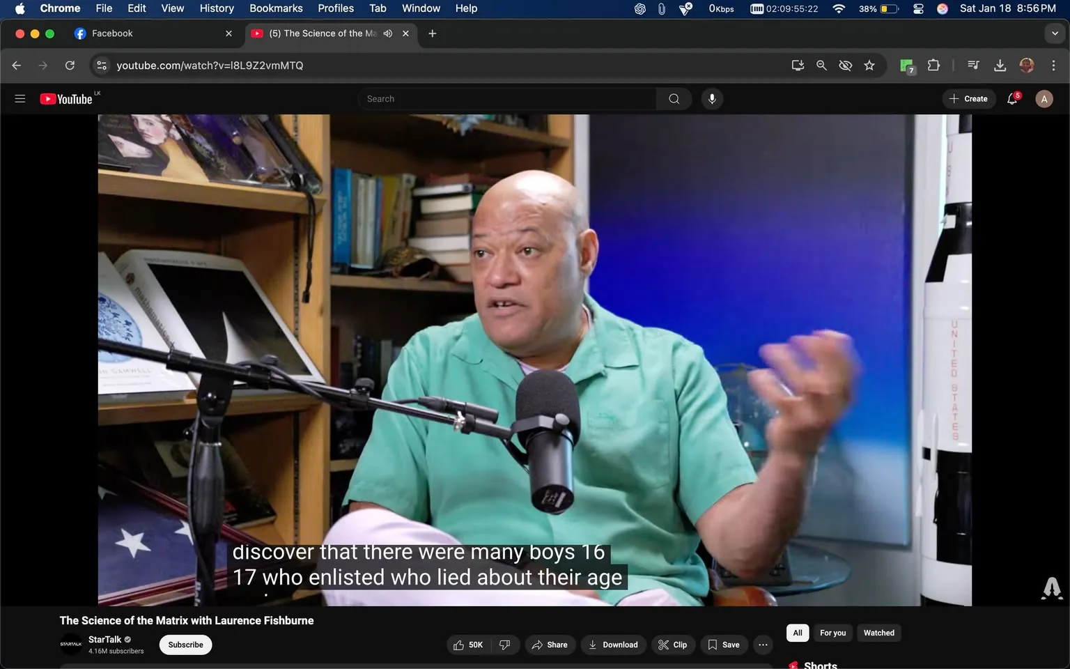 In the image, an unidentified adult is seated in a studio environment, engaged in a discussion. They are wearing a green shirt and are animatedly speaking into a microphone, gesturing with their hands. The background features shelves filled with books and other items, suggesting a scholarly atmosphere. A blue gradient backdrop is visible behind them, enhancing the focus on the speaker. Subtitles are displayed at the bottom of the image, indicating that the person is discussing historical enlistment practices among young boys during a specific period. There are no visible brands or logos in the image. The overall setting appears to be a recording studio, likely for a podcast or video series.