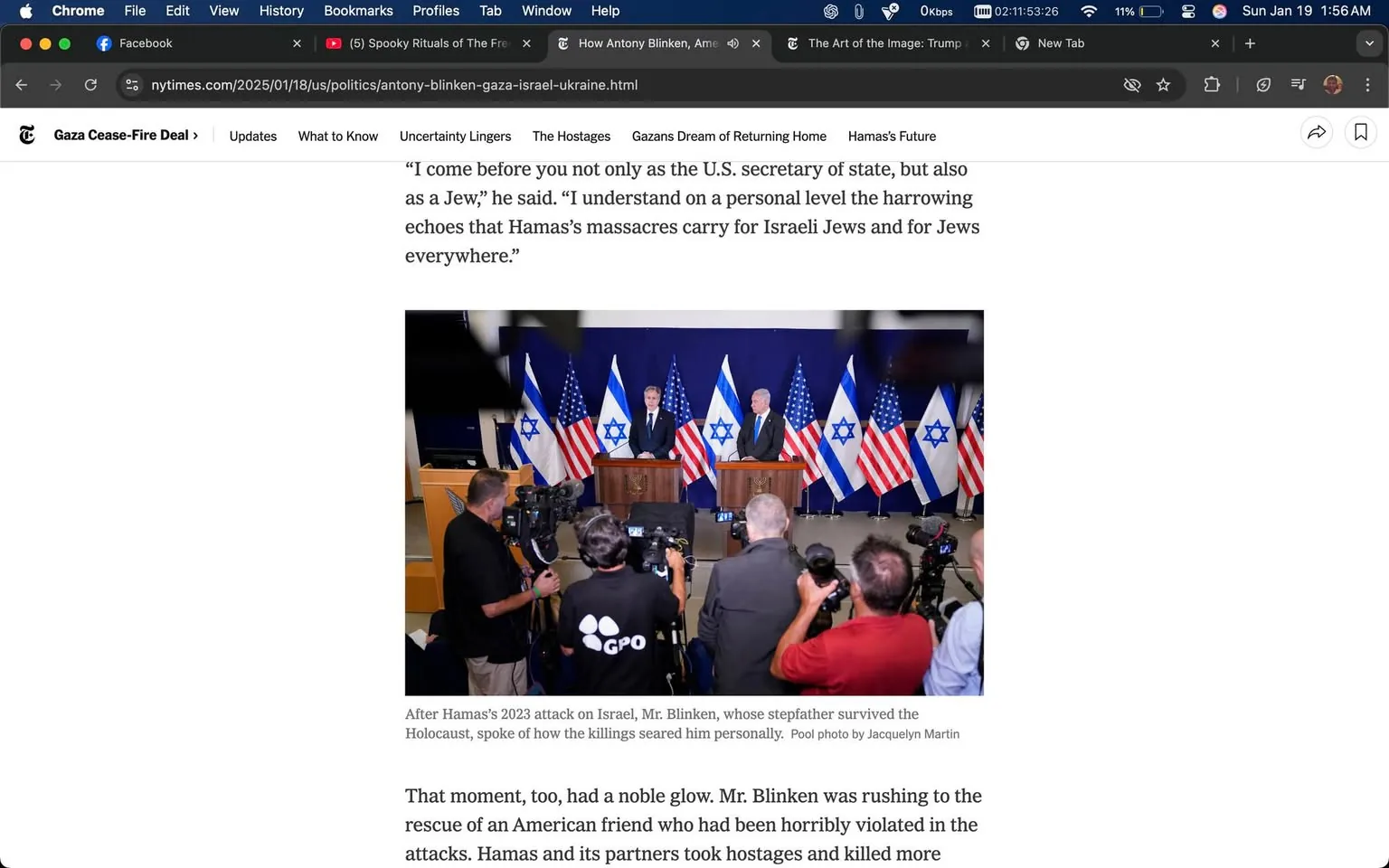 In the image, U.S. Secretary of State Antony Blinken stands at a podium alongside another official, both addressing a gathering. The backdrop features multiple Israeli flags and American flags, indicating a diplomatic setting. Blinken appears serious and engaged, reflecting the gravity of the situation discussed. The audience consists of several photographers and journalists, capturing the moment with cameras and recording devices. The atmosphere suggests a press conference or official statement regarding recent events, likely related to the ongoing conflict involving Hamas. The presence of the flags emphasizes the political nature of the event. The text visible on the podium indicates it is associated with the Government Press Office (GPO). There are no visible signs of violence or sexual content in the image, focusing instead on the political discourse taking place.