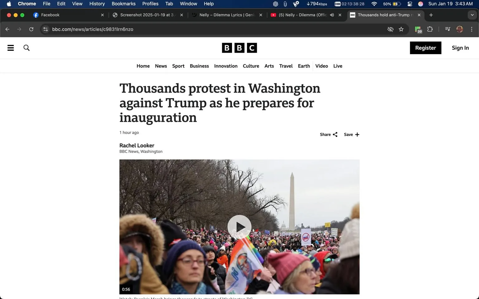 Thousands of people are gathered in Washington, D.C., protesting against Donald Trump as he prepares for his inauguration. The scene is outdoors, likely during the day, with a cloudy sky overhead. In the foreground, a diverse group of individuals can be seen, many wearing winter clothing such as hats and scarves, indicating it is a chilly day. Some participants are holding signs, which may express various messages against Trump, although the text on the signs is not clearly visible in the image.

The crowd appears to be large, stretching back towards the Washington Monument, which is a prominent feature in the background. The monument stands tall and is easily recognizable, serving as a landmark for the event. The atmosphere seems charged with energy, as people are engaged in the protest, some looking directly at the camera with serious expressions. The overall setting conveys a sense of unity among the protesters, who are gathered to voice their dissent.