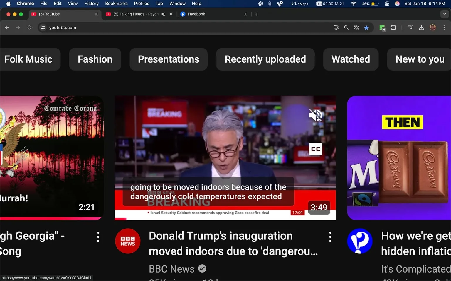 In the image, a news segment is being broadcast, featuring an unidentified adult male presenter with gray hair and glasses, who appears to be reading from a script. He is dressed in a dark suit and white shirt, and the background shows a newsroom setting with multiple screens displaying news graphics. The text on the screen indicates that the discussion is about an event related to Donald Trump's inauguration, specifically mentioning that it was moved indoors due to dangerously cold temperatures. The lower part of the screen displays the BBC News logo, indicating the source of the broadcast. The overall atmosphere is serious, reflecting the nature of the news being reported.